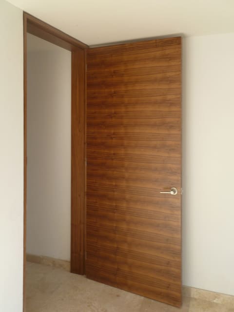 Puerta de madera de nogal para interior instalada en dormitorio.