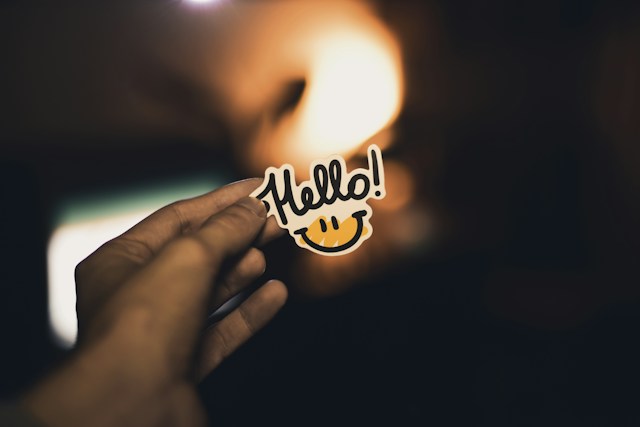 A Person holding a small cutout showing the word 'Hello!' with a smiley face underneath