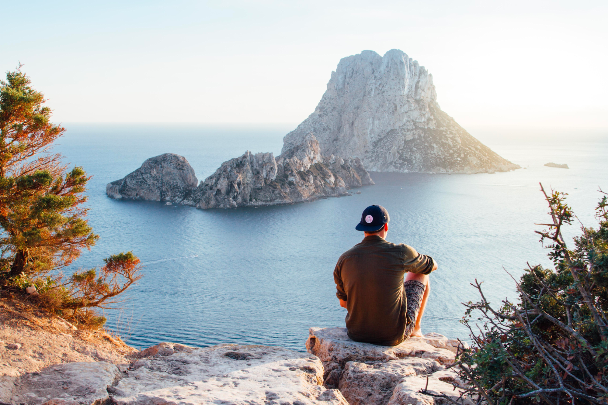 man sitting near the water on an island