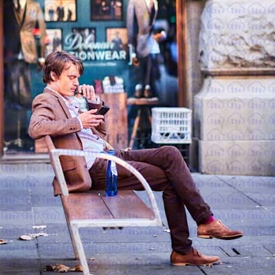 cloudinary watermark tiled on an image of a man sitting on bench