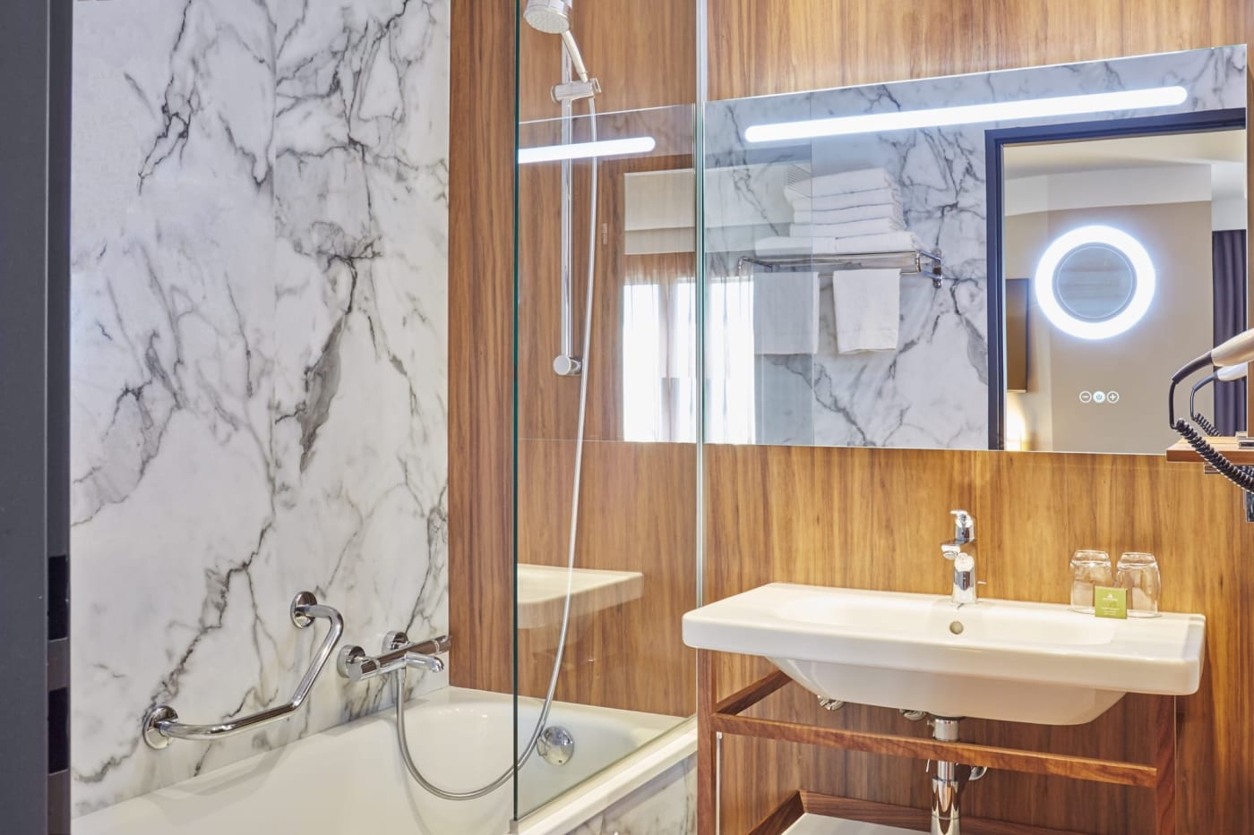 Ein Badezimmer aus Marmor und Holz im Hôtel l'Élysée Val d'Europe