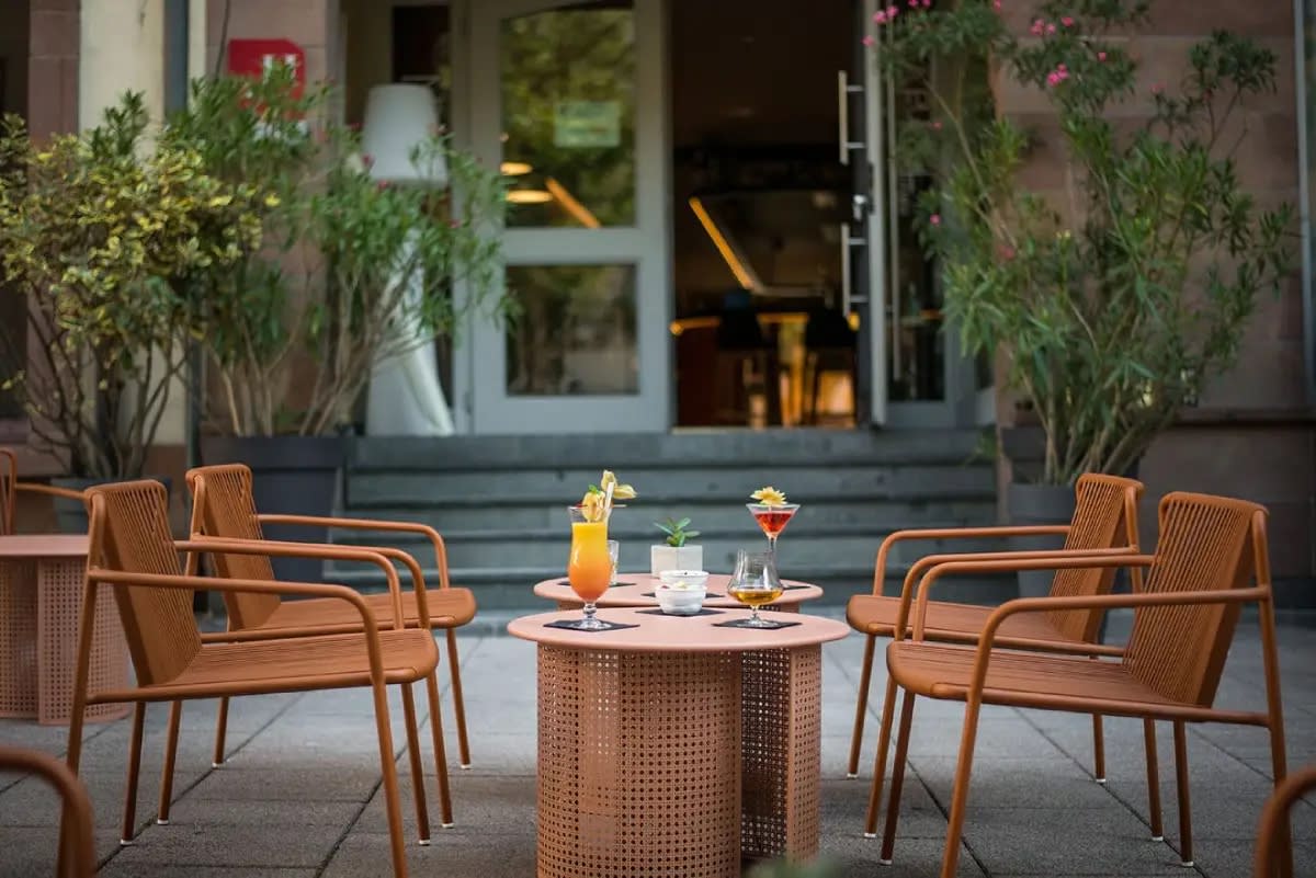 Der gläserne Eingang des Hôtel Rohan und seine Terrasse mit kupferfarbenen Sesseln