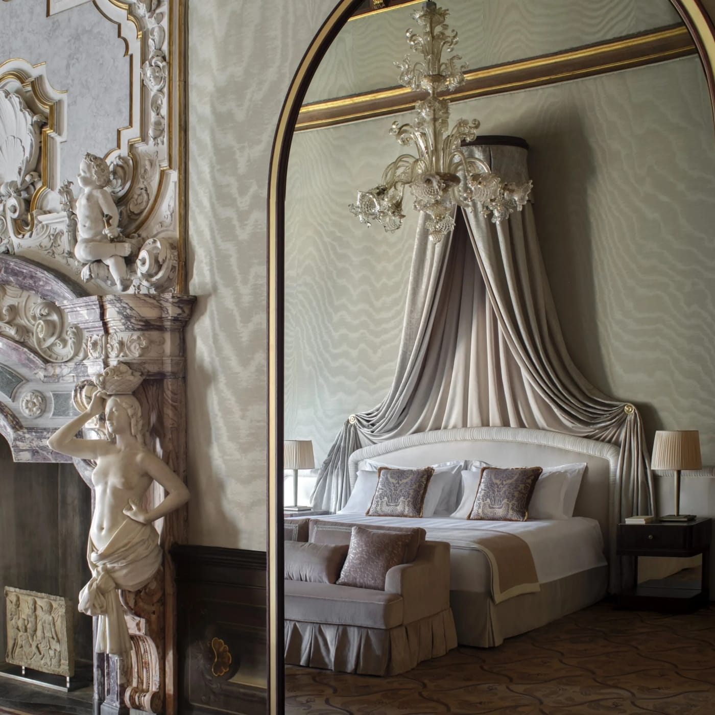 Ein Zimmer im Orient Express Venezia mit Himmelbett, geschnitztem Kamin und Glasleuchter