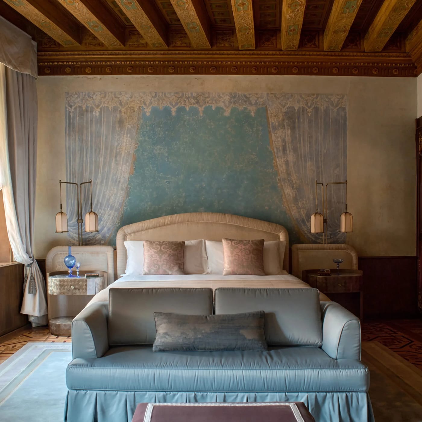 Ein Zimmer im Orient Express Venezia, pastellblaues Bett, Sichtbalken und bemalte Wandbespannung