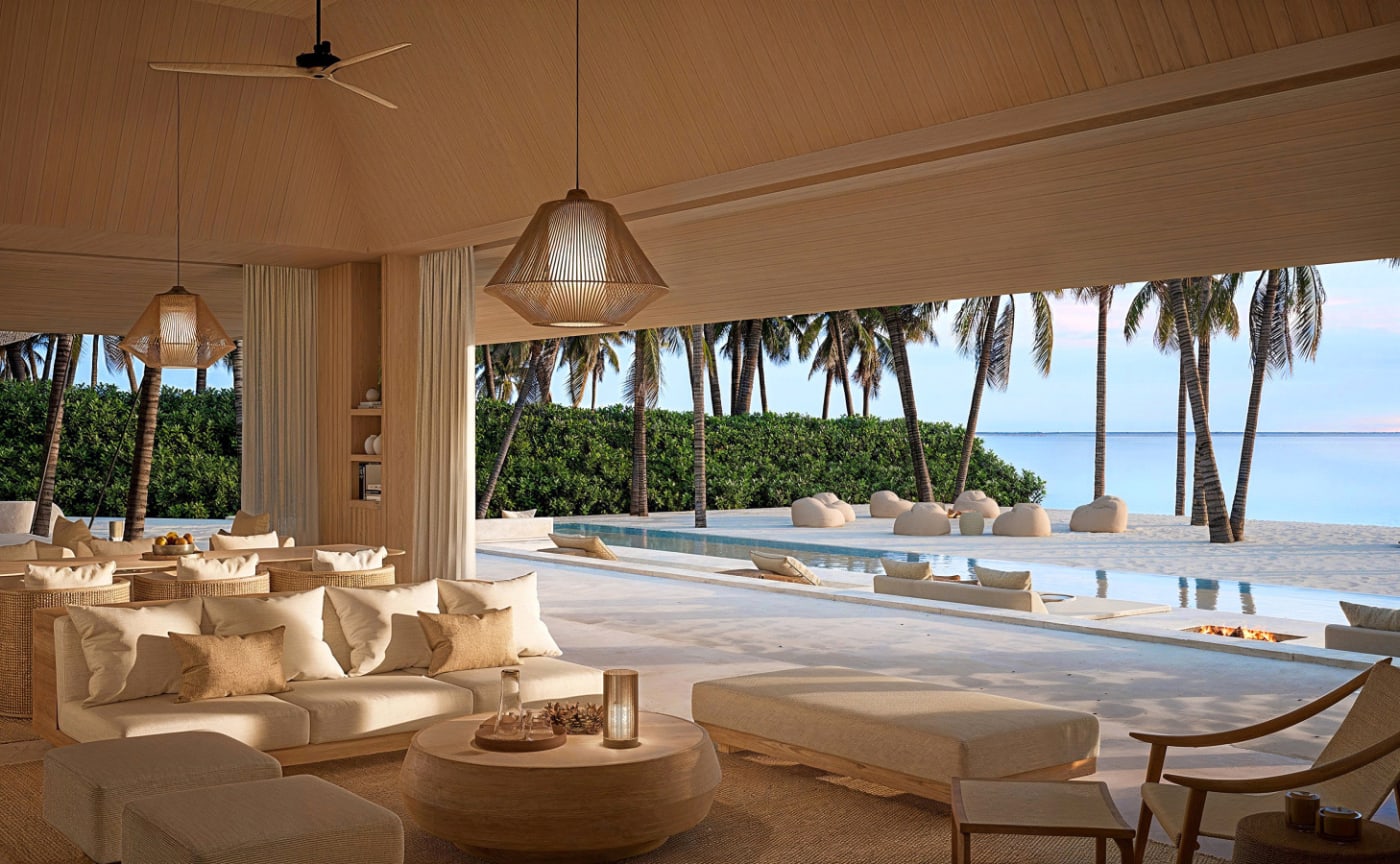 Le salon d'un pavillon en bord de plage de l'Aman Maldives, palmiers et piscine