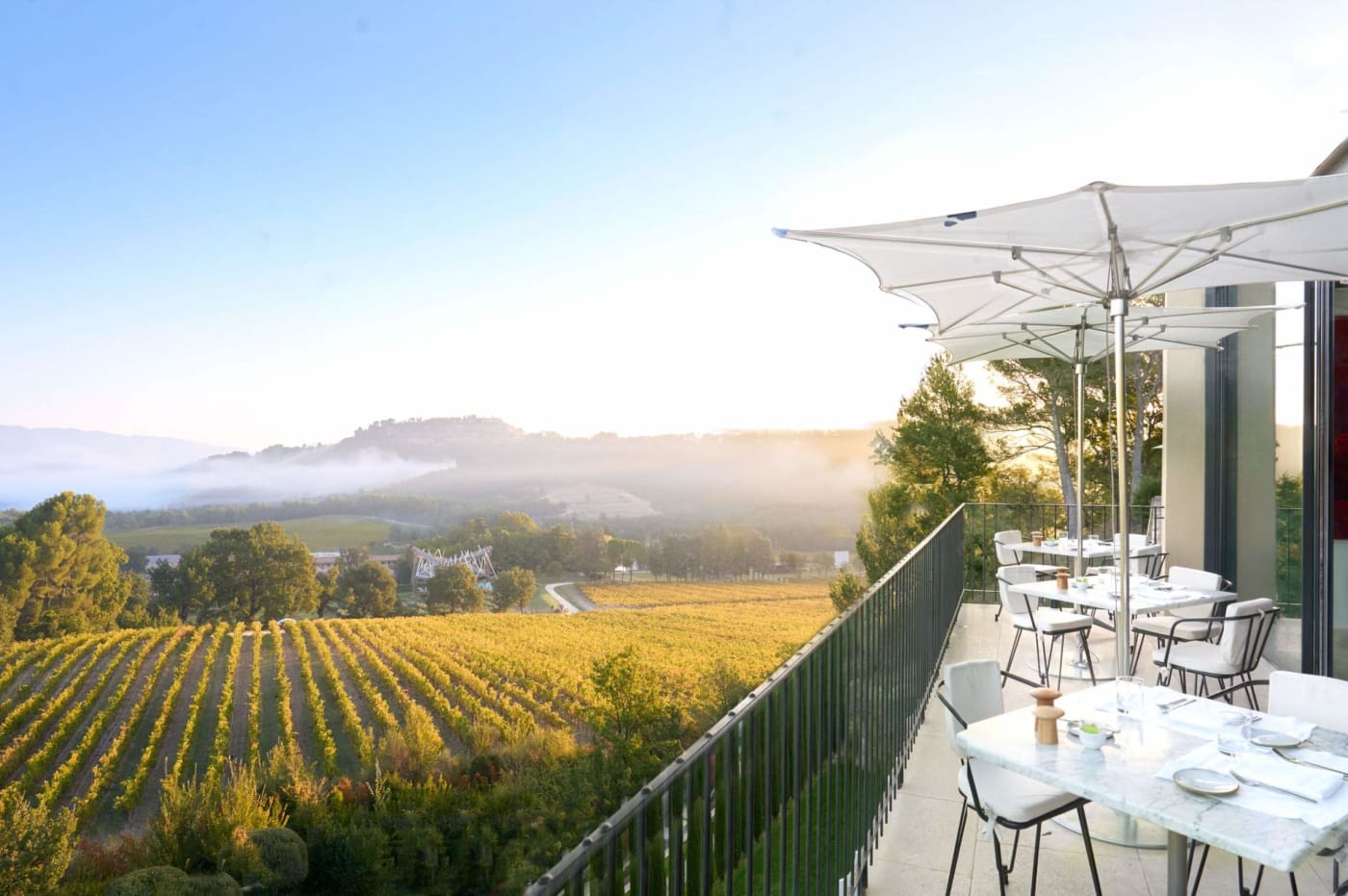 Terrace of La Galerie restaurant at Villa La Coste laid for breakfast, above the vines in the morning mist