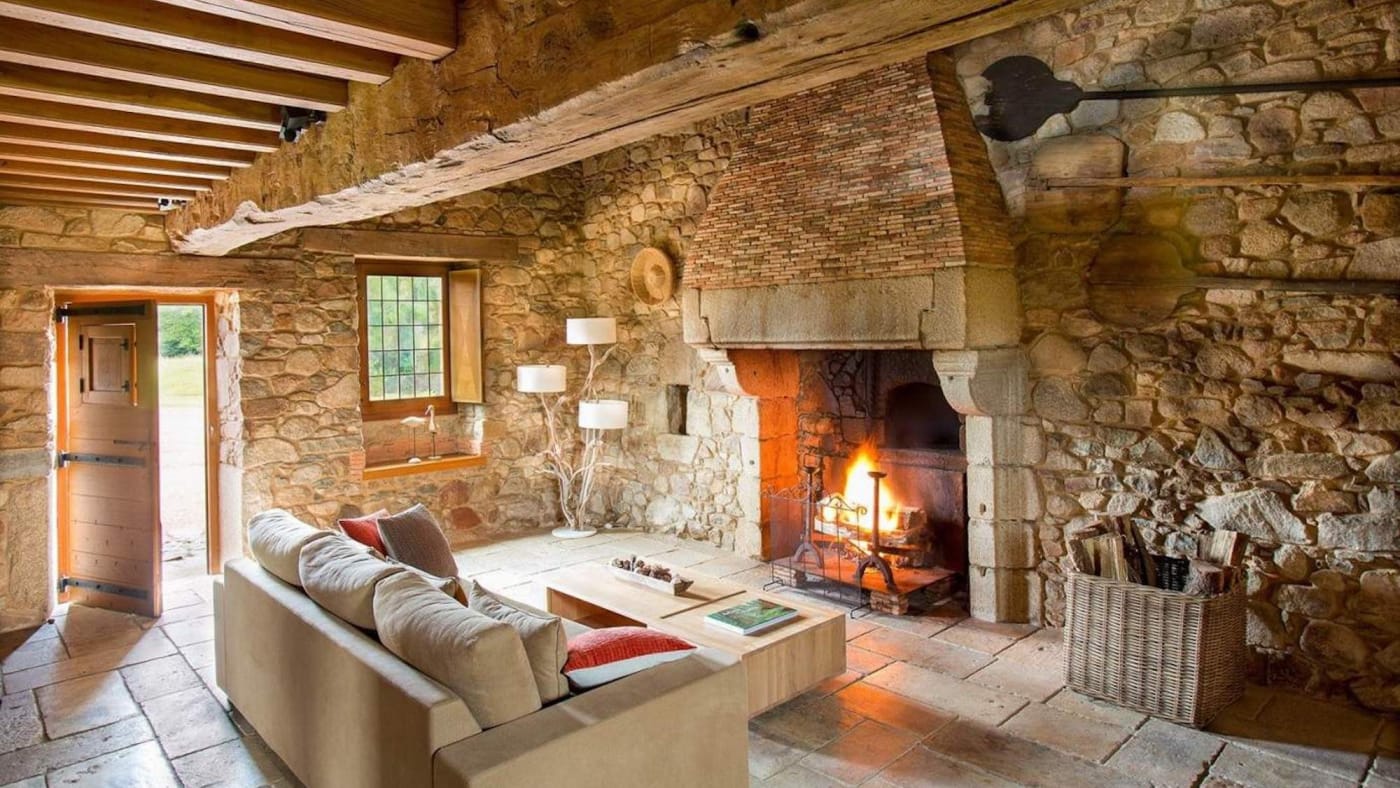 Fire in the large stone fireplace of a Métairie cottage at the Domaine des Étangs