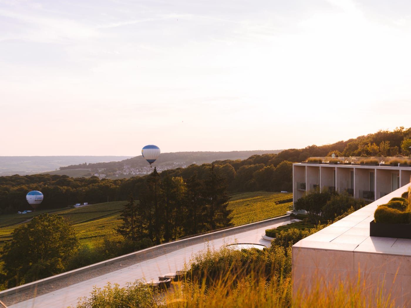 Sunset over the terraces of the Royal Champagne Hotel & Spa in Champillon, with hot-air balloons above the Champagne slopes