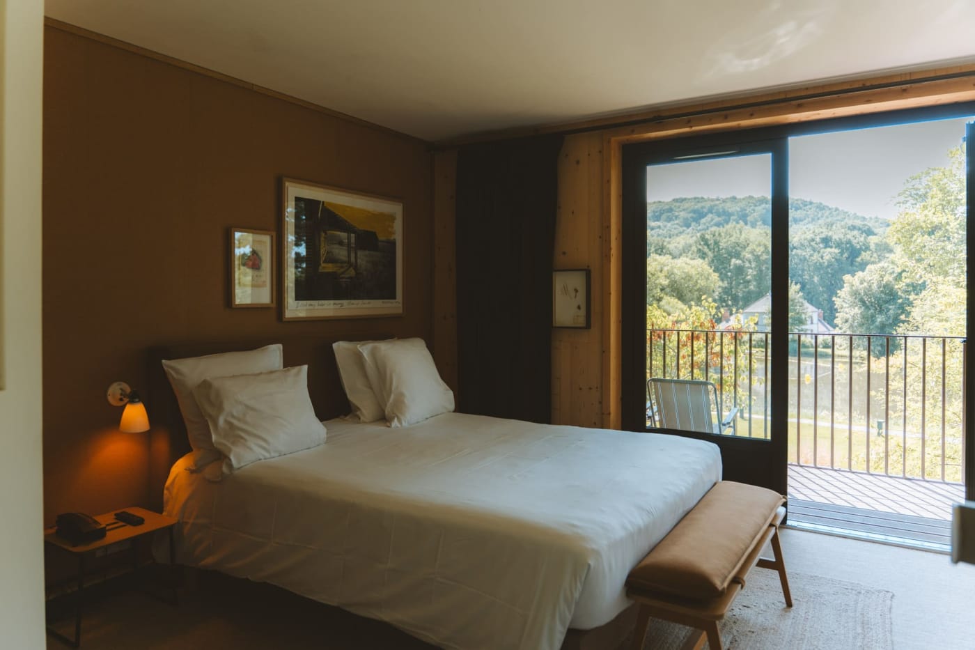 Bedroom at Le Barn in Bonnelles with ochre walls, opening onto a balcony facing the forest