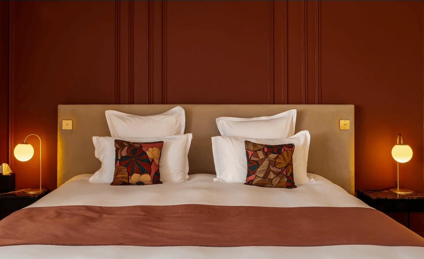 Bedroom at the Domaine de Rochebois with terracotta walls, a large bed and embroidered cushions