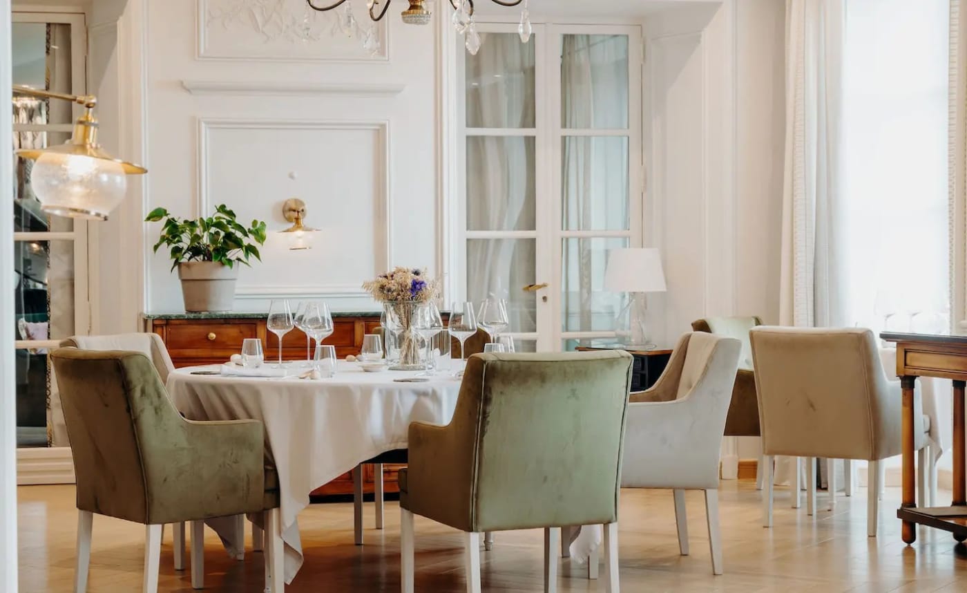 The bright dining room of Le M restaurant at the Domaine de Rochebois, with laid tables and mouldings