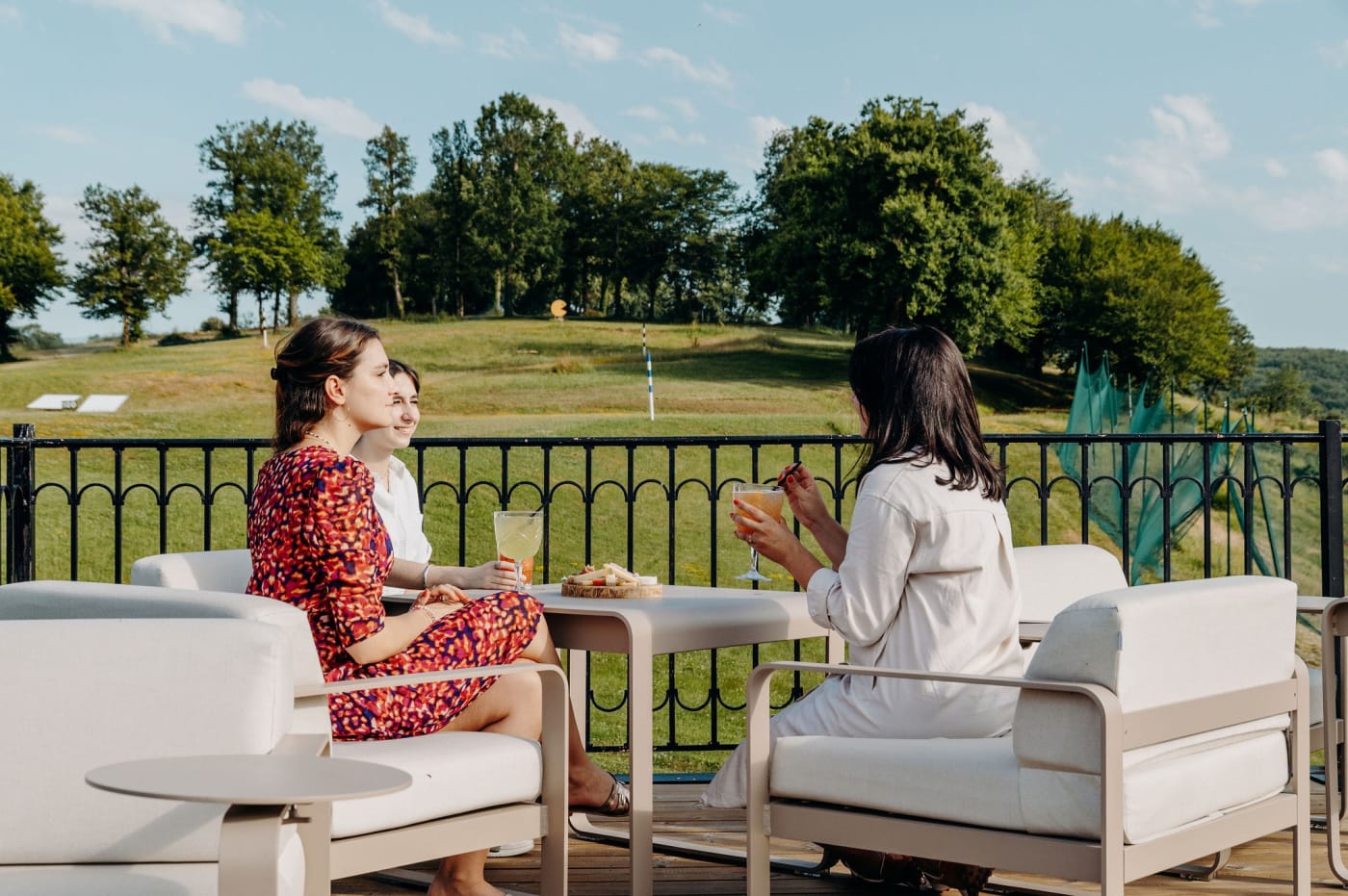 Two guests enjoy a drink on the terrace of the Domaine de Rochebois overlooking the rolling grounds