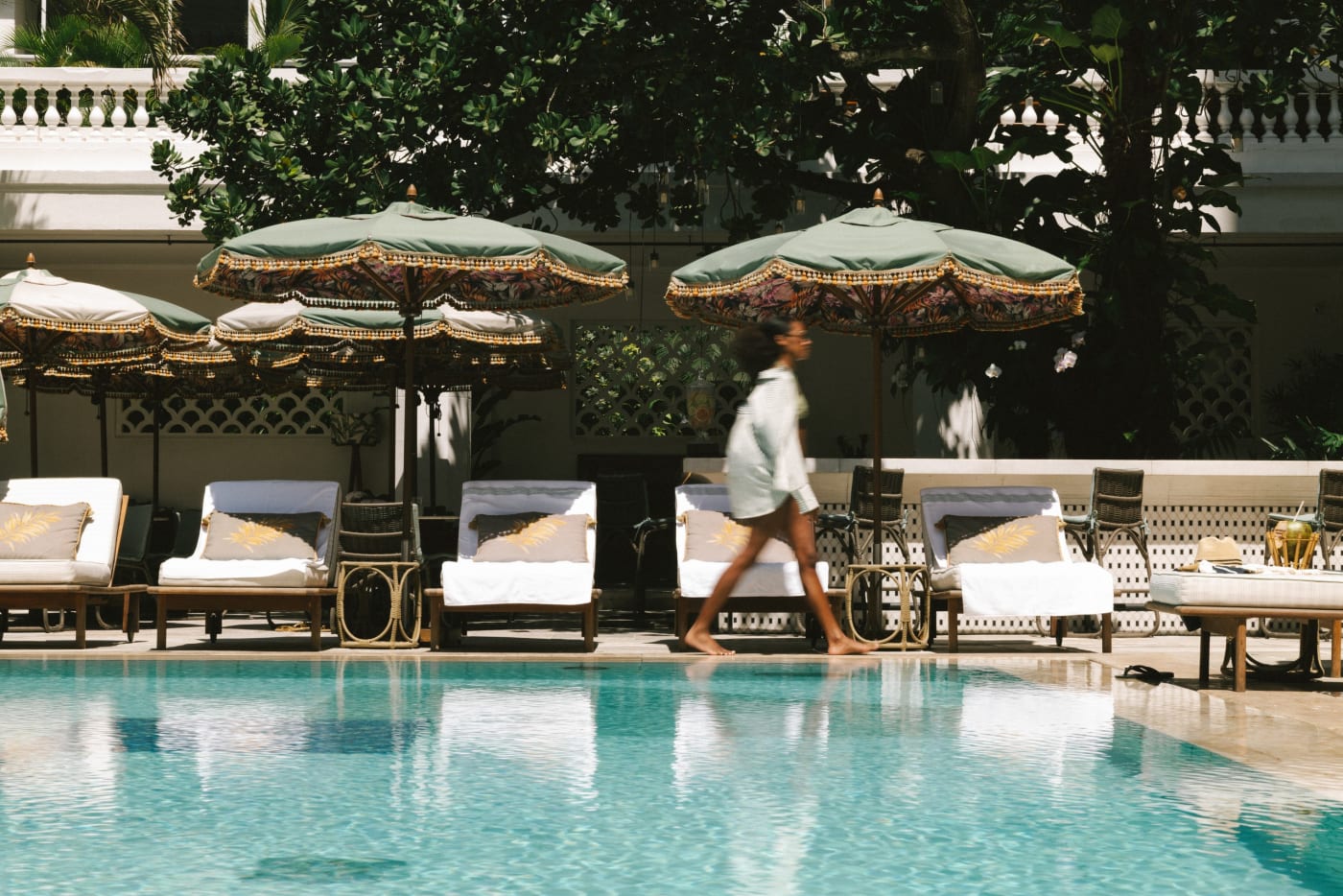 A piscina do Copacabana Palace, no Rio de Janeiro, com espreguiçadeiras e guarda-sóis sob as árvores