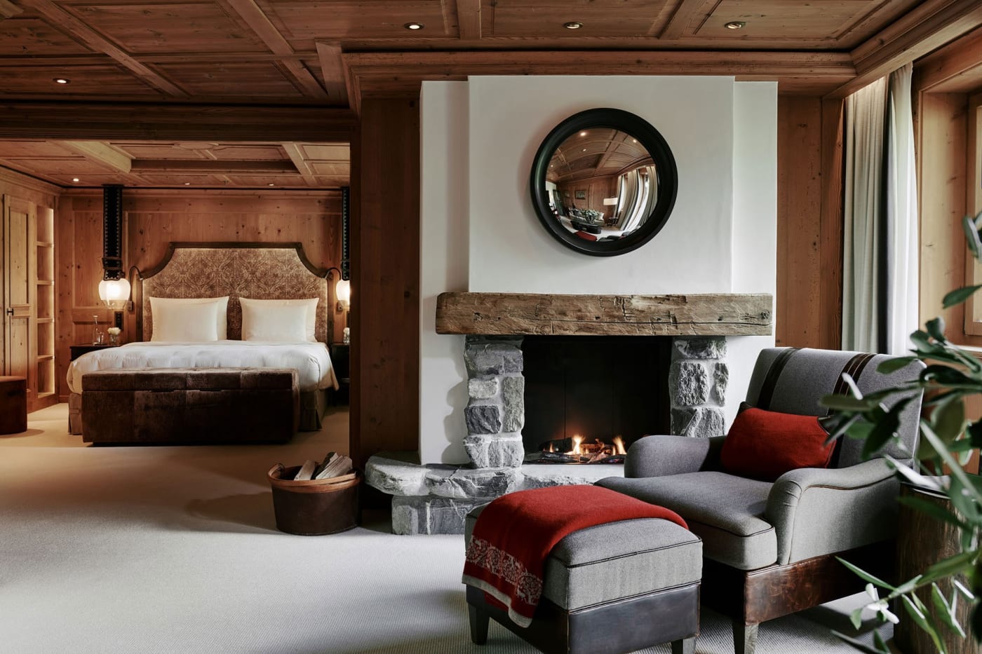 Suite de The Alpina Gstaad avec cheminée en pierre, boiseries et fauteuil gris