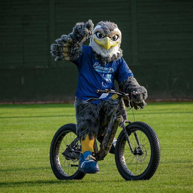 Riverhawks mascot River riding an electric bike and waving