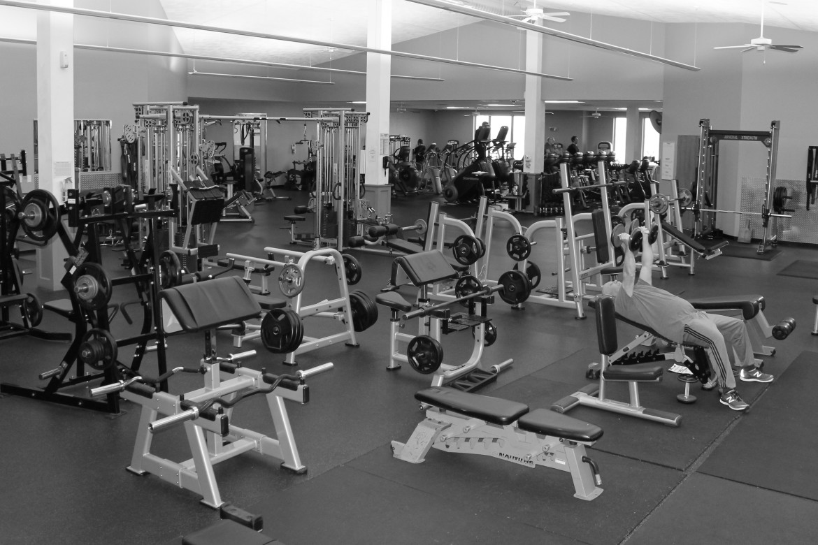 B/W image of gym floor with wide assortment of benches, free weight and other equipment. equipment