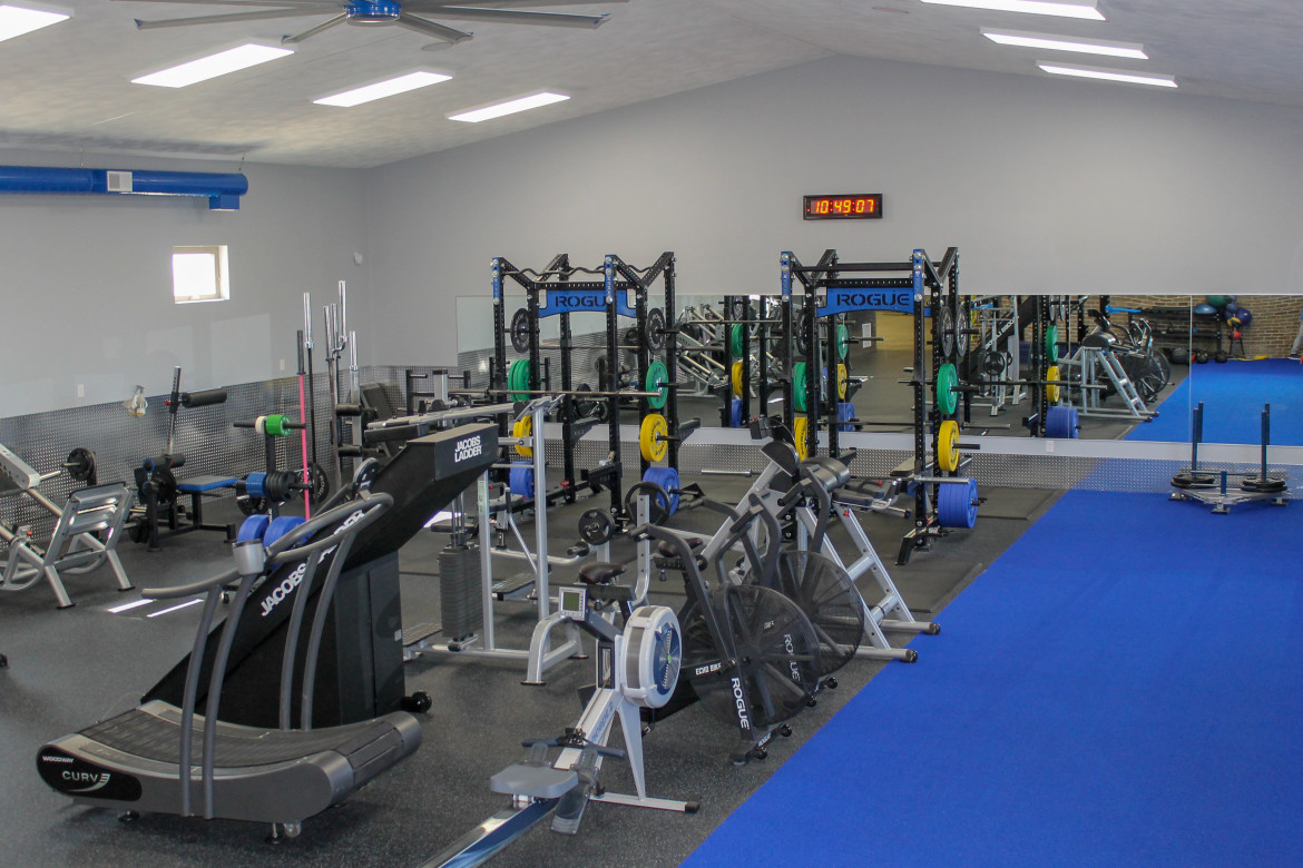 View of gym floor with racks and free weights all over.