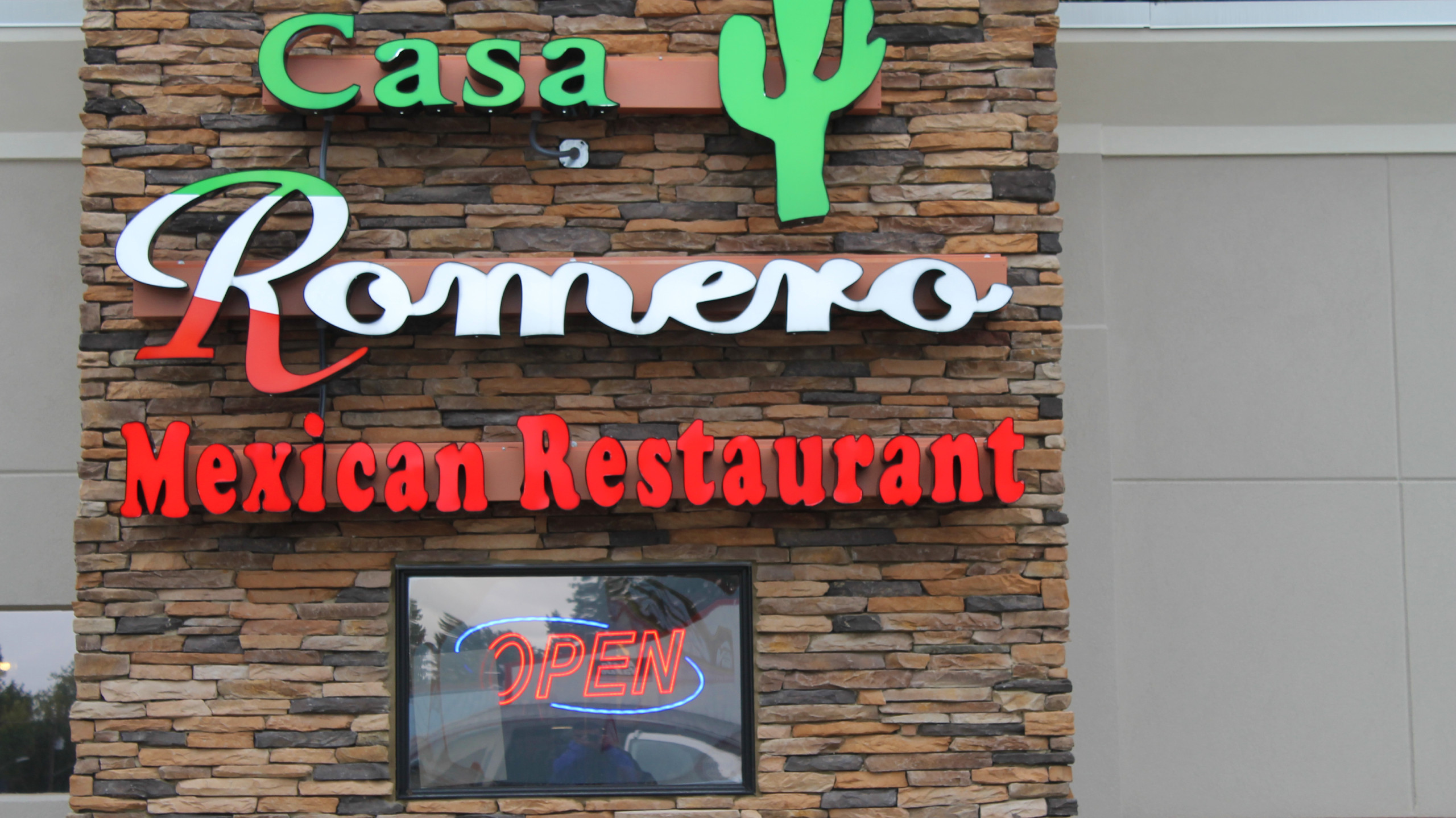 Casa Romero Mexican Restaurant digital sign on outside wall with open neon sign in the window.