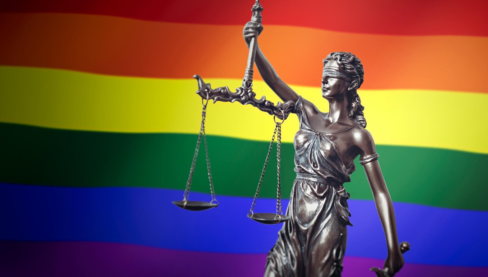 Dei Justitia with the rainbow flag in the background