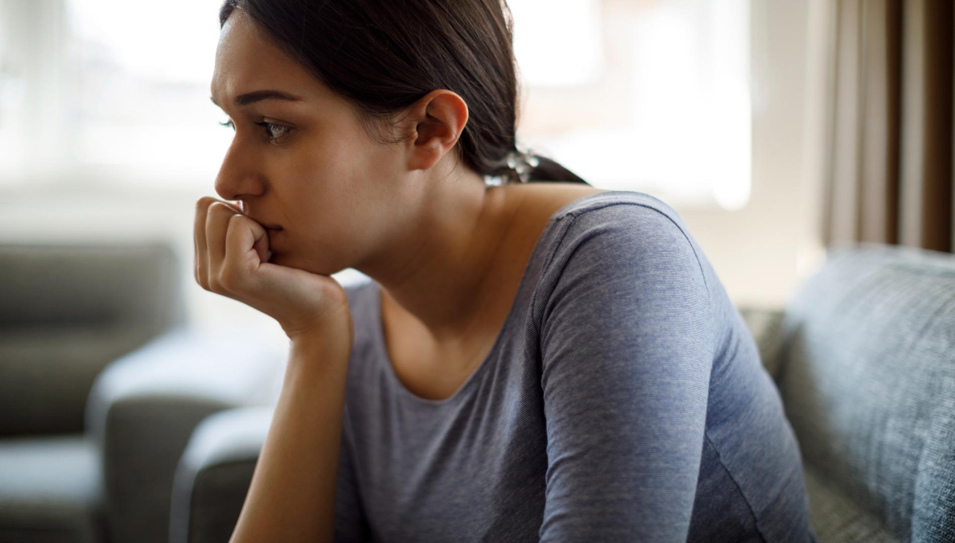 Upset woman sitting on sofa alone at home