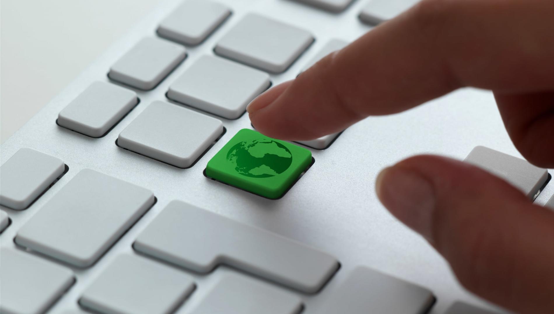 A finger hovering a solitary green key, signifying the planet, on an all-white keyboard