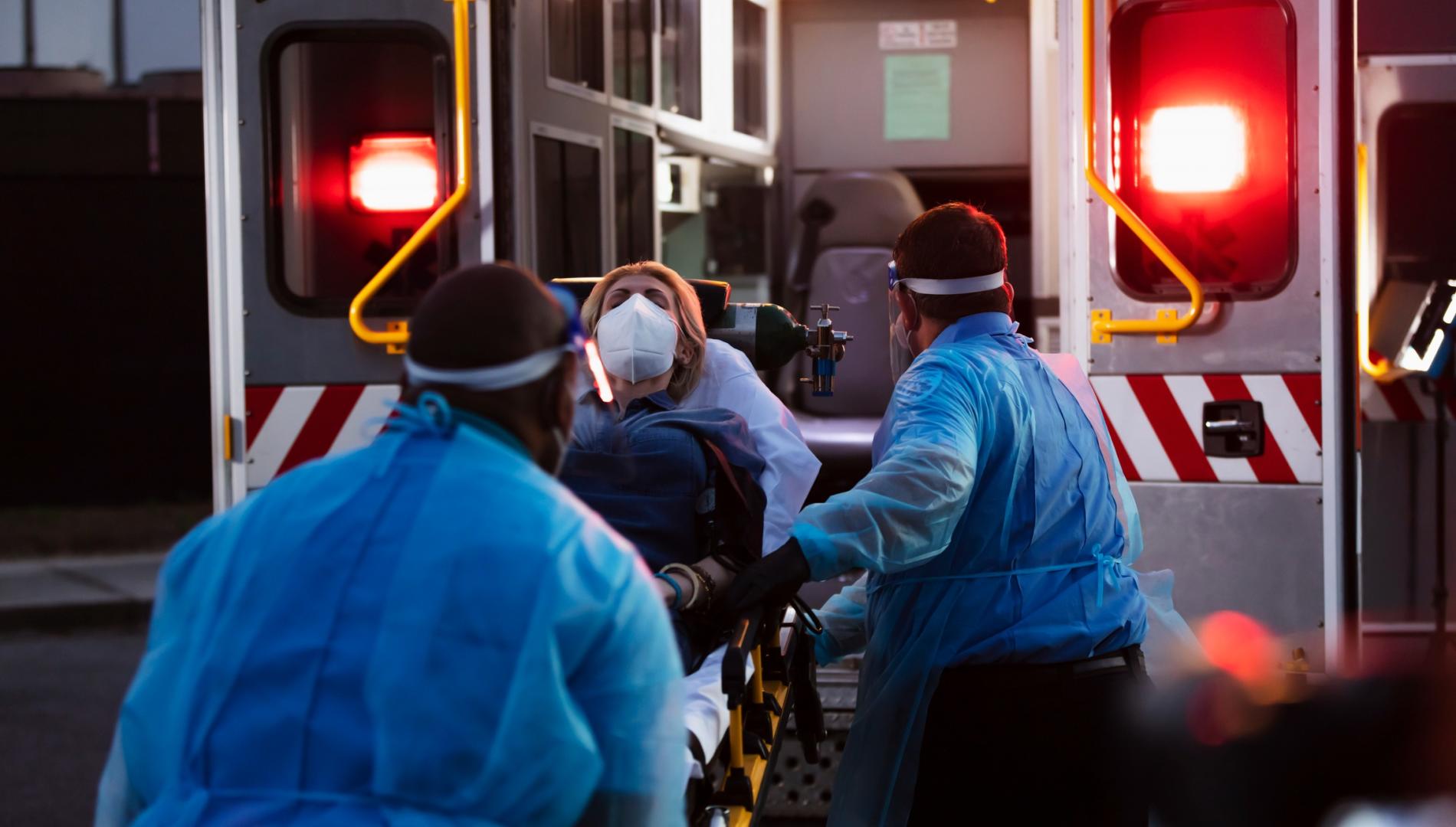 Paramedics wheel a woman onto an ambulance.