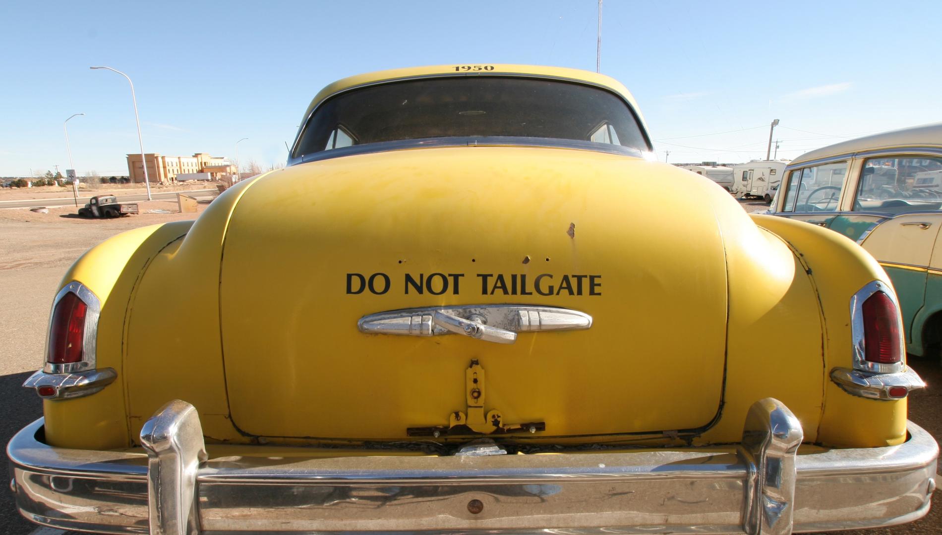 Old yellow car with message stencilled on the rear deck.