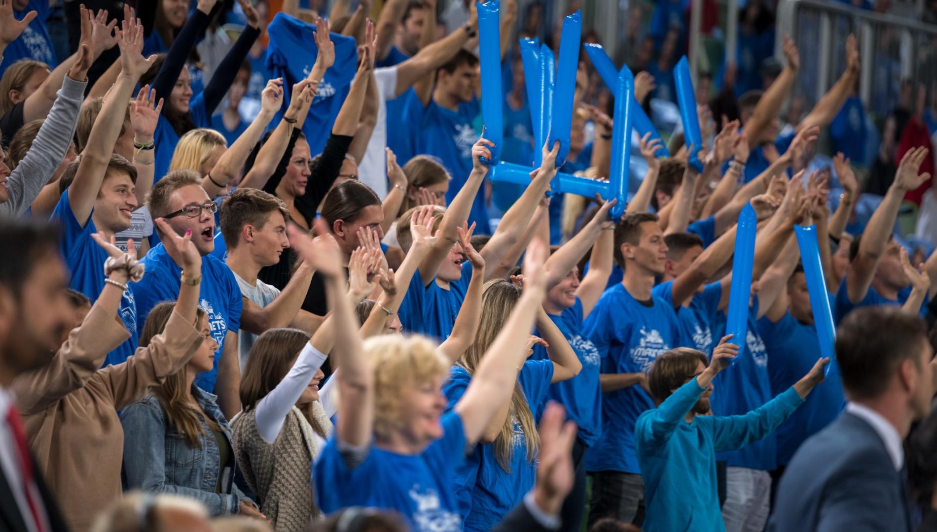 Spectators cheering in a stadium during a basketball match.