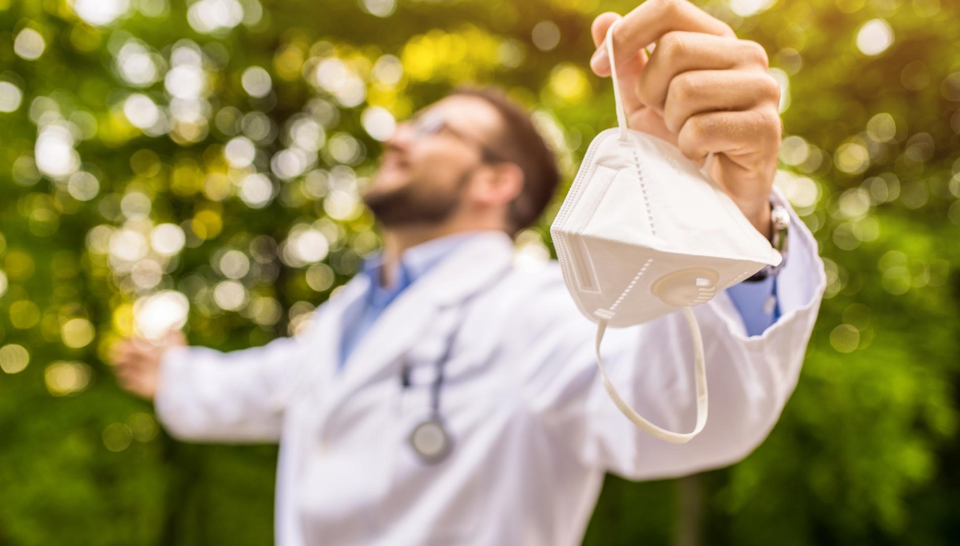 Happy doctor in an outdoor setting with his arms outstretched.