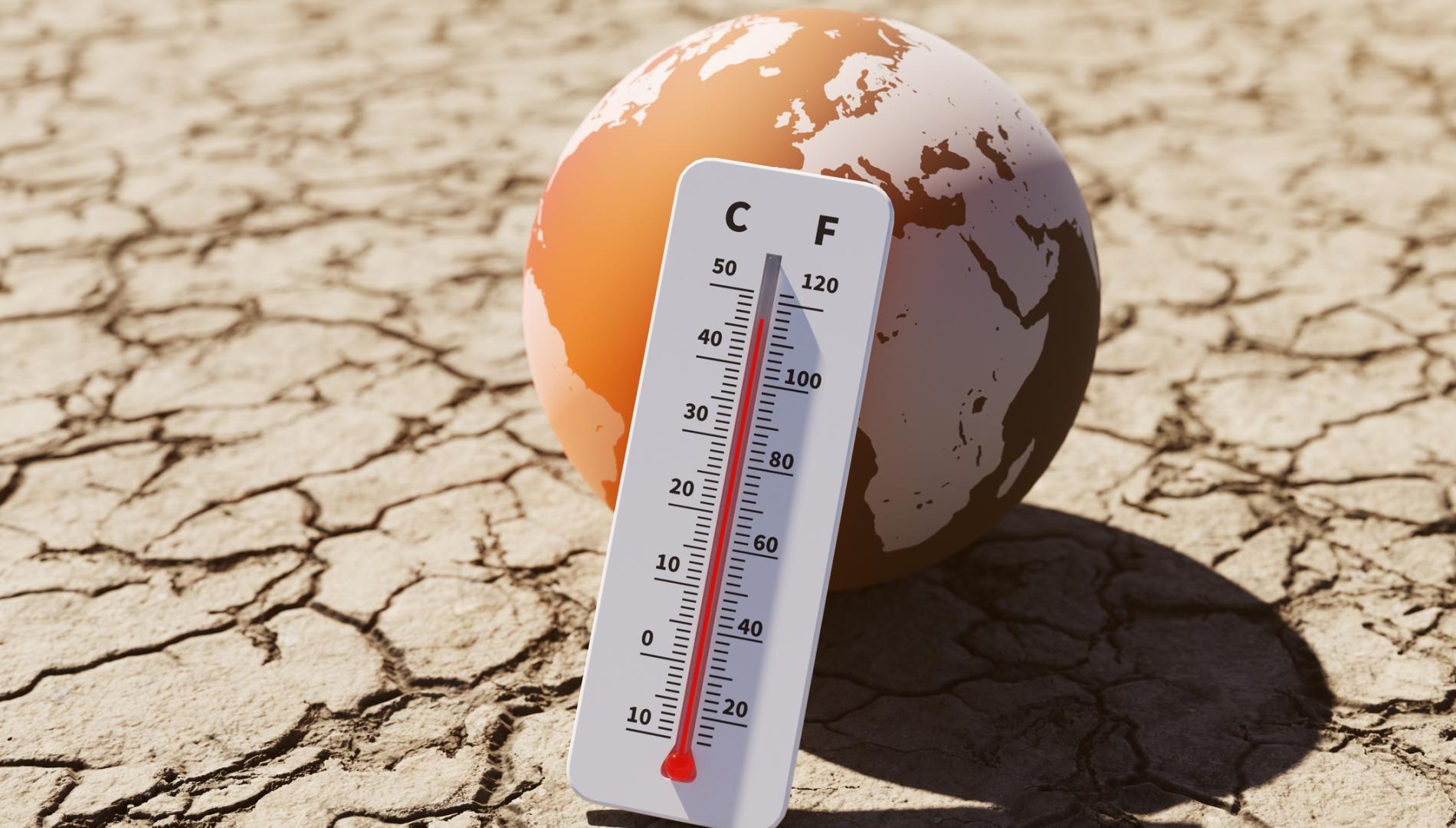 Global map and thermometer on cracked earth.