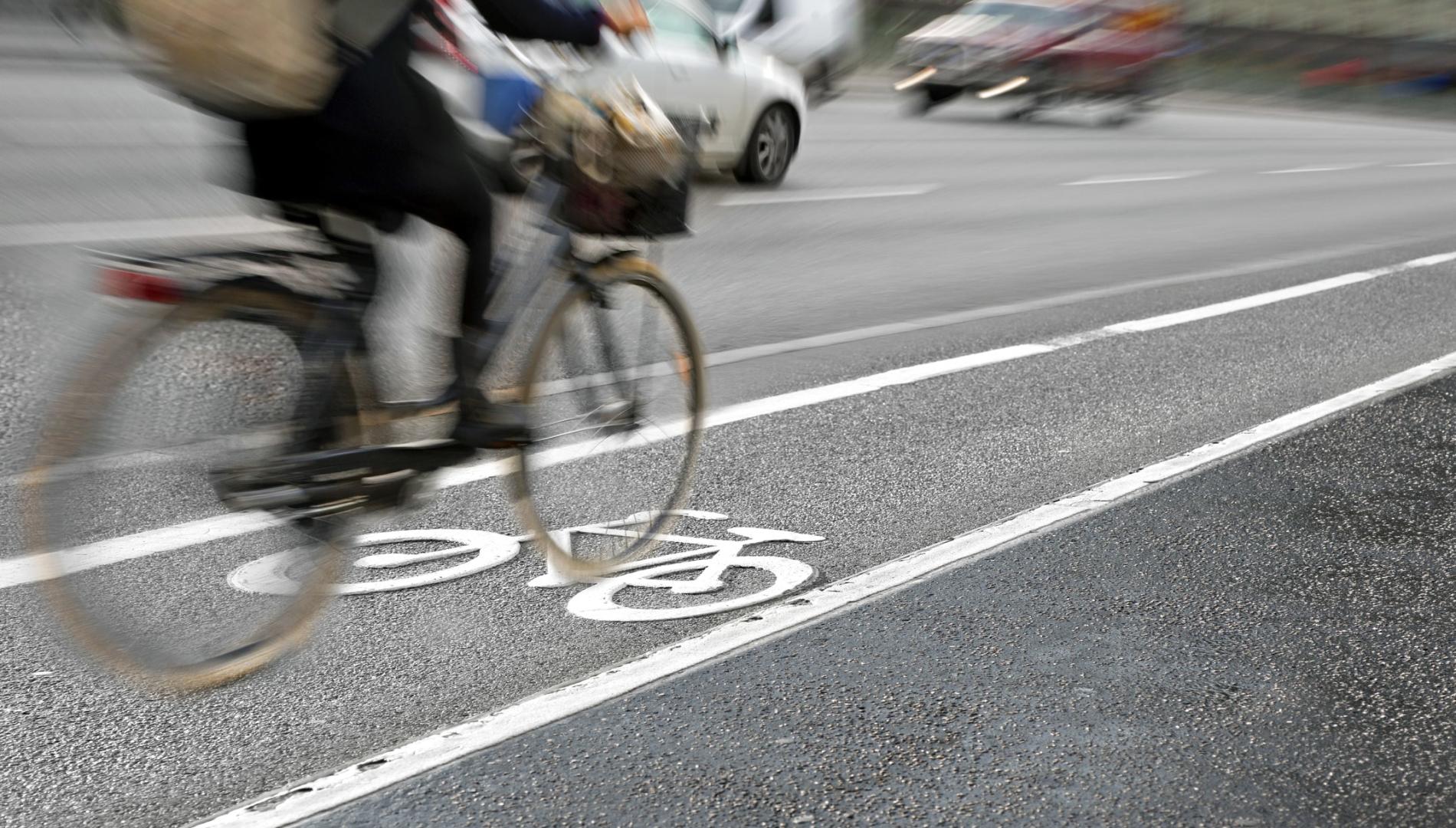 Blurred image of a woman riding in a bike lane beside traffic