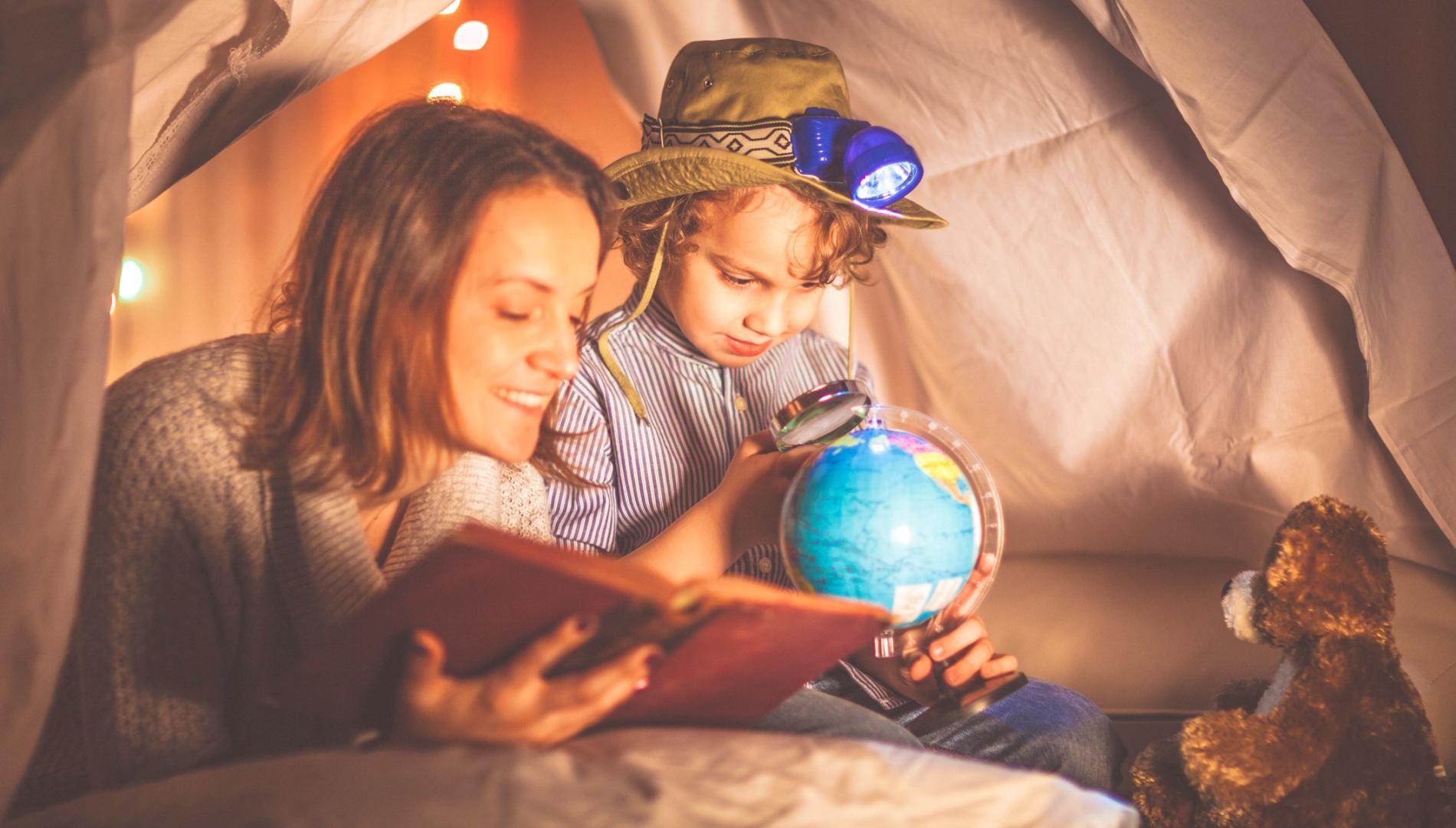 Mother reads a bedtime story to a child who is looking at a map of the world.