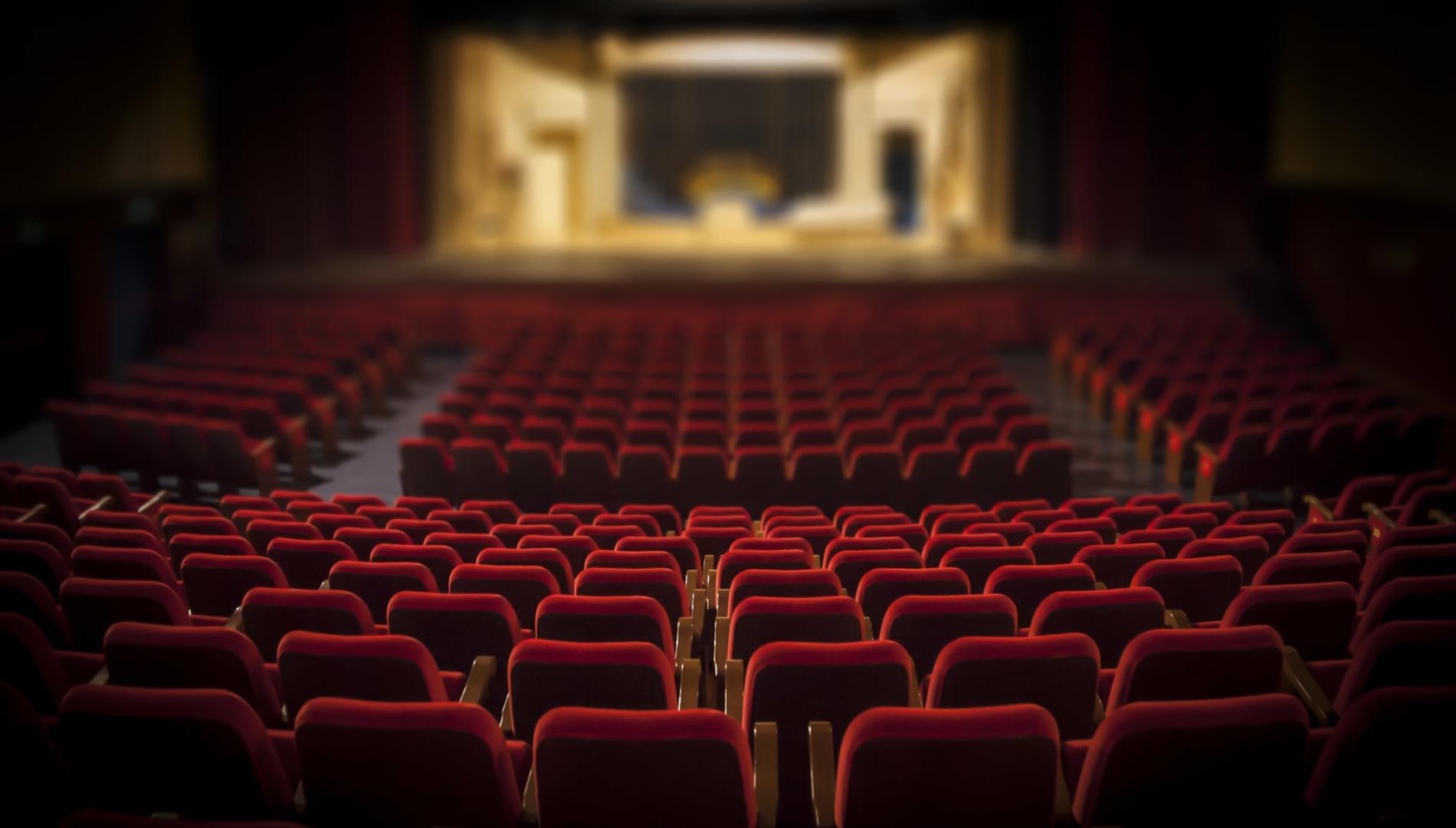 An empty theatre with plush red seats