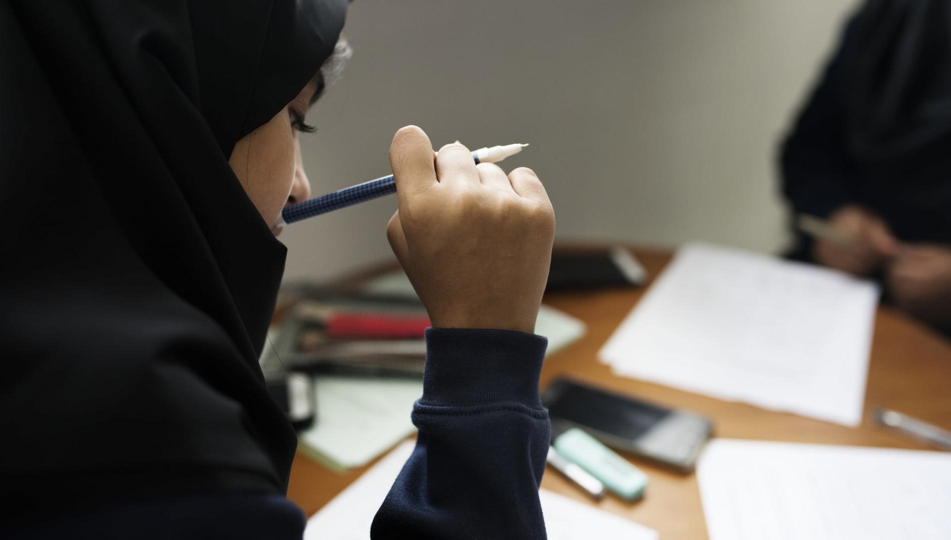 Young Muslim student doing schoolwork at her desk