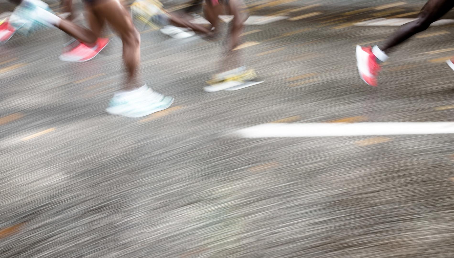 Blurred legs of runners on a road