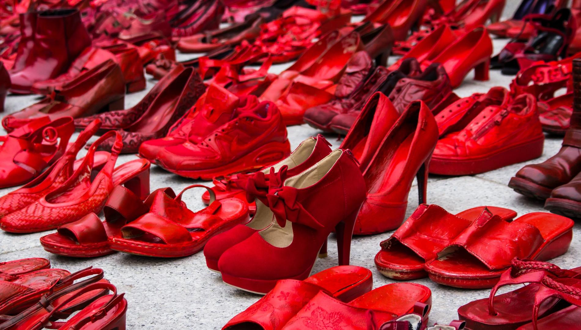 Multiple pairs of red shoes on a concrete floor as a symbol against violence.