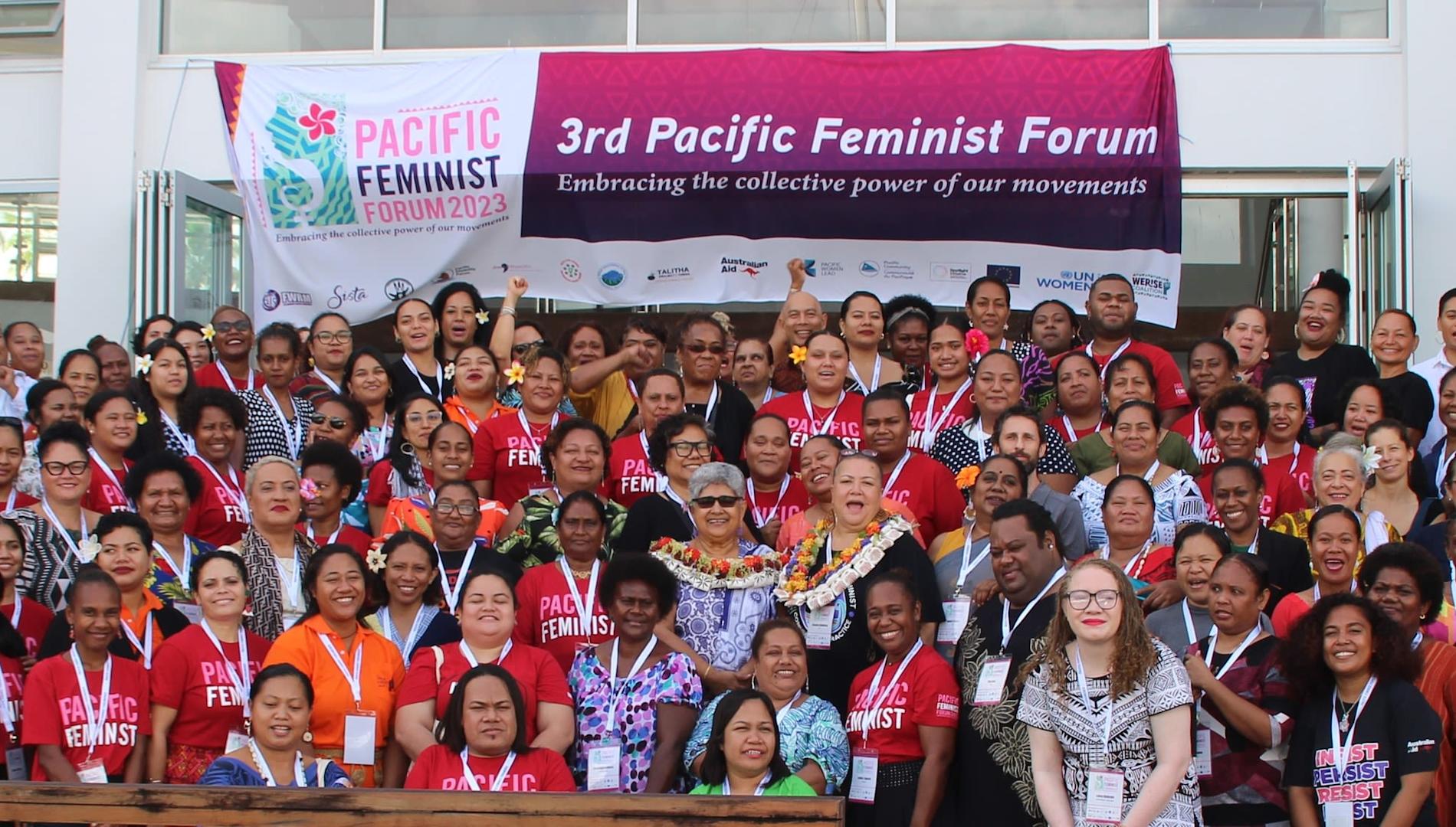 Group photo of activists in front of a banner for the third Pacific Feminist Forum