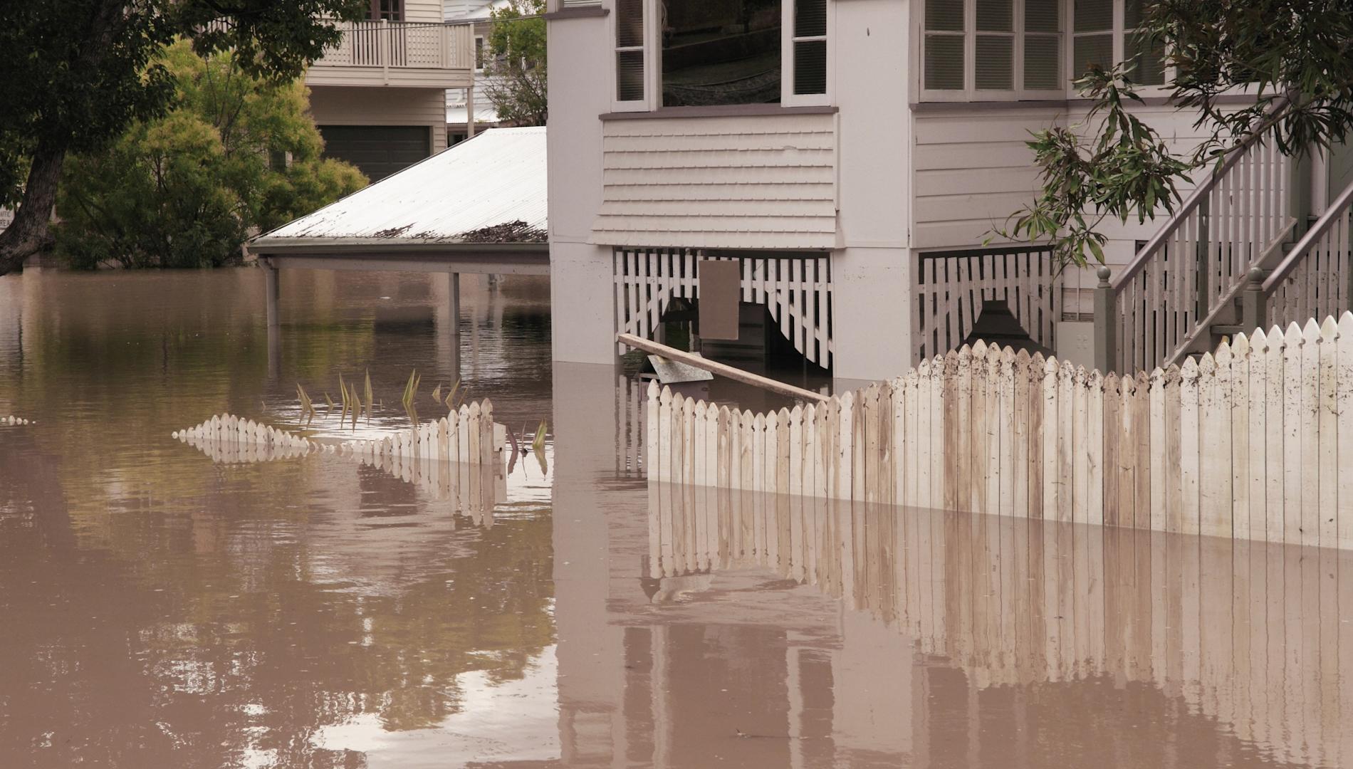 Landscape view of house flooded several feet deep.