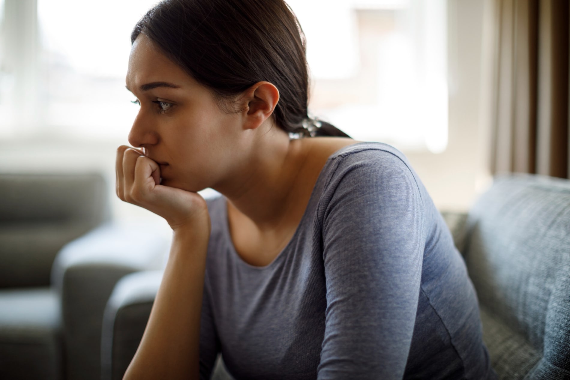 Upset woman sitting on sofa alone at home