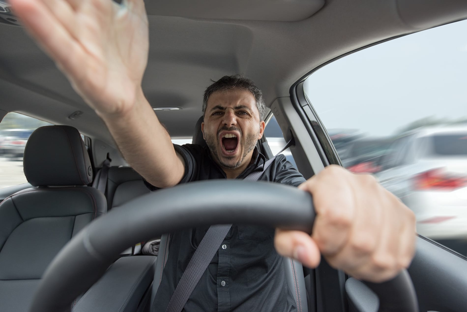 Angry, yelling man behind the steering wheel of his vehicle
