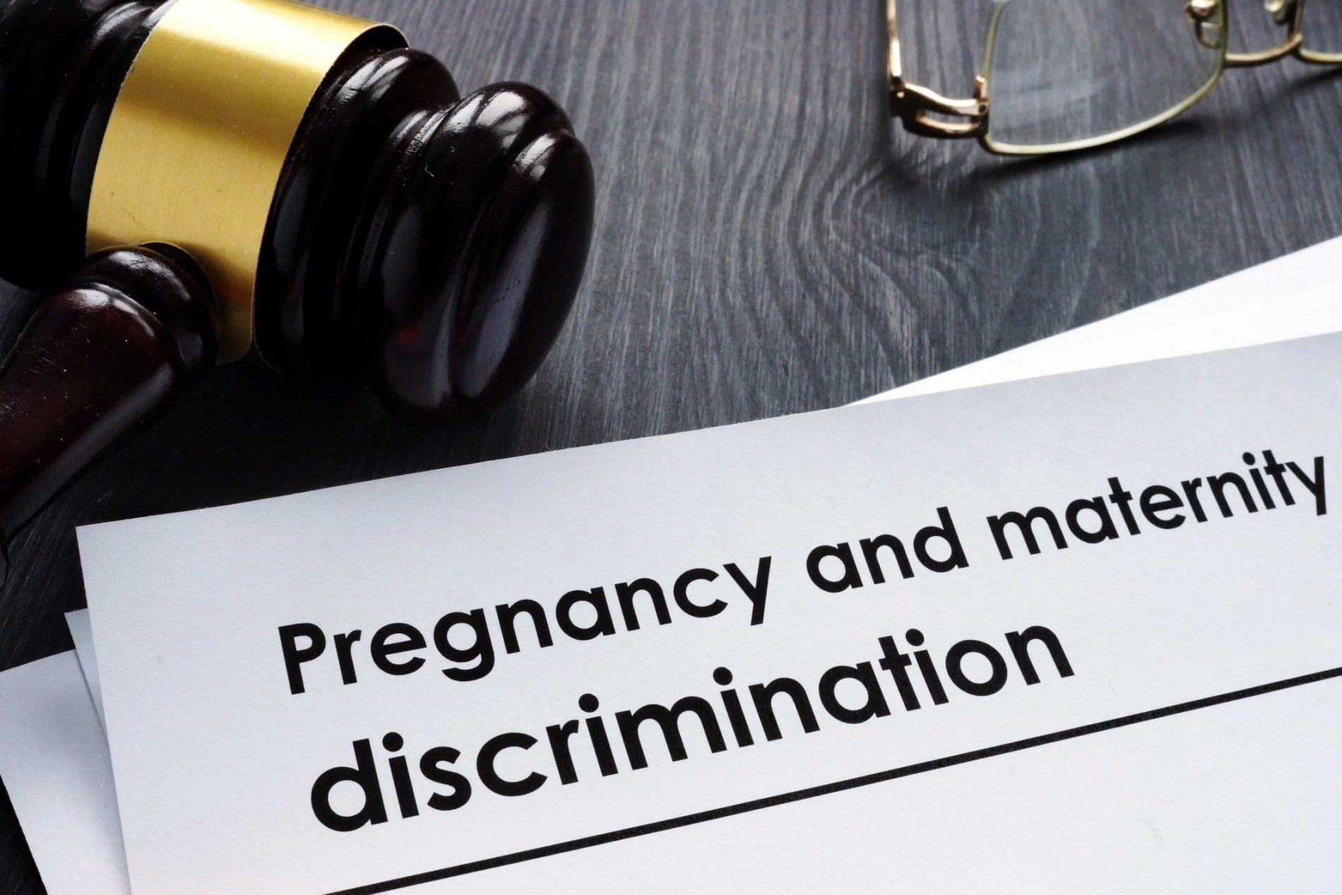 Paper with the heading 'Pregnancy and maternity discrimination' on a desk with a judge's gavel