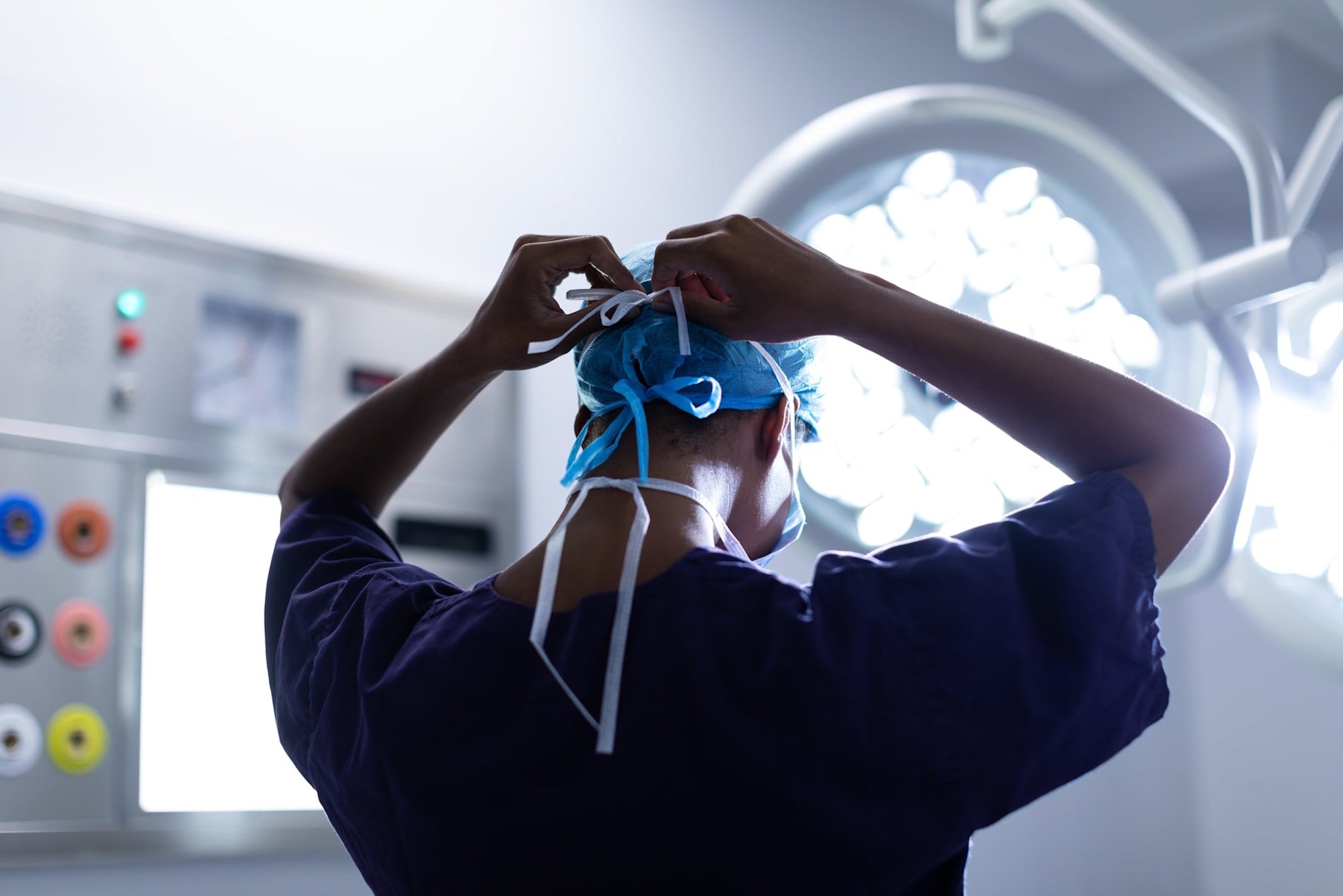 Female surgeon tying on a surgical mask in an operating theatre