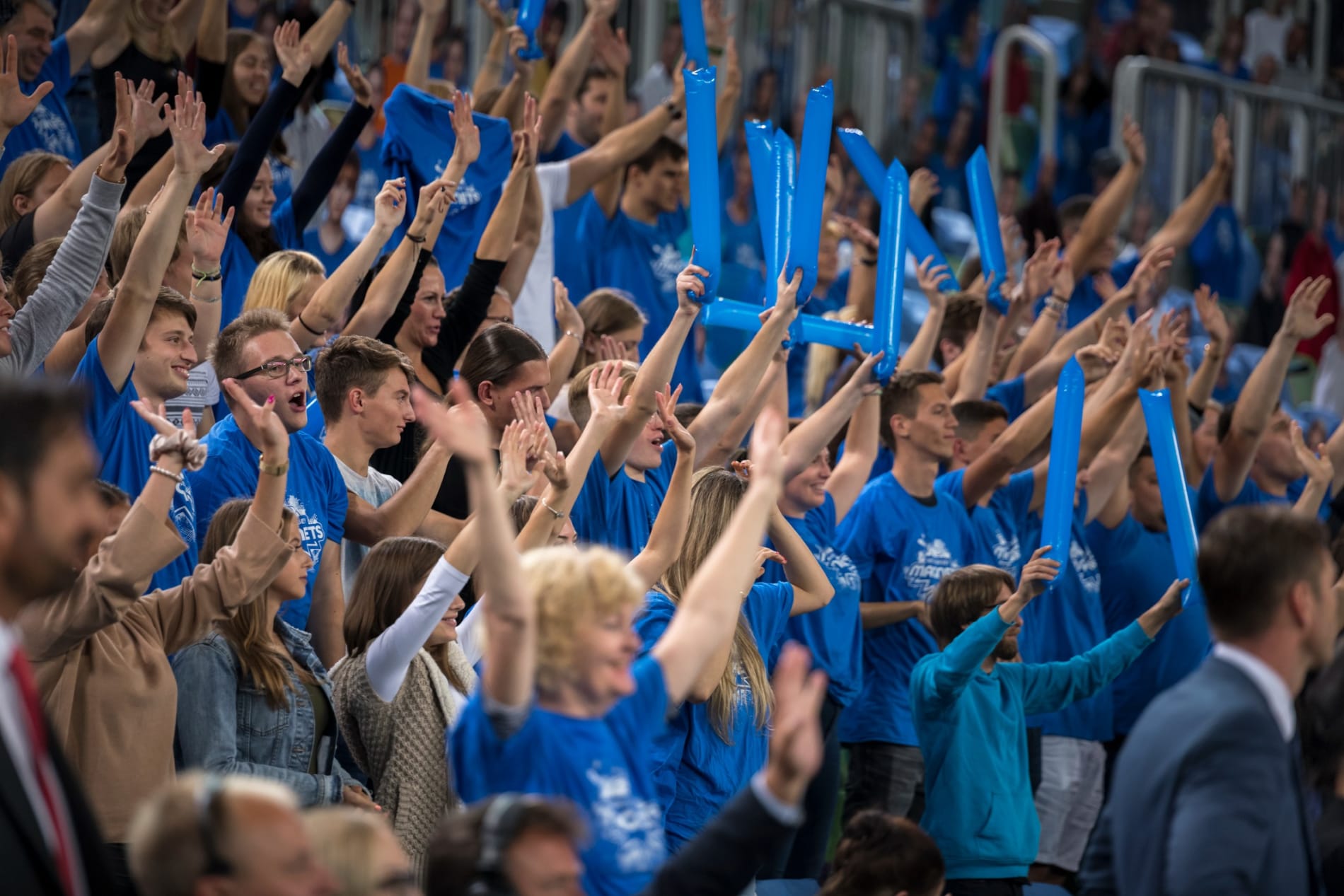 Spectators cheering in a stadium during a basketball match.