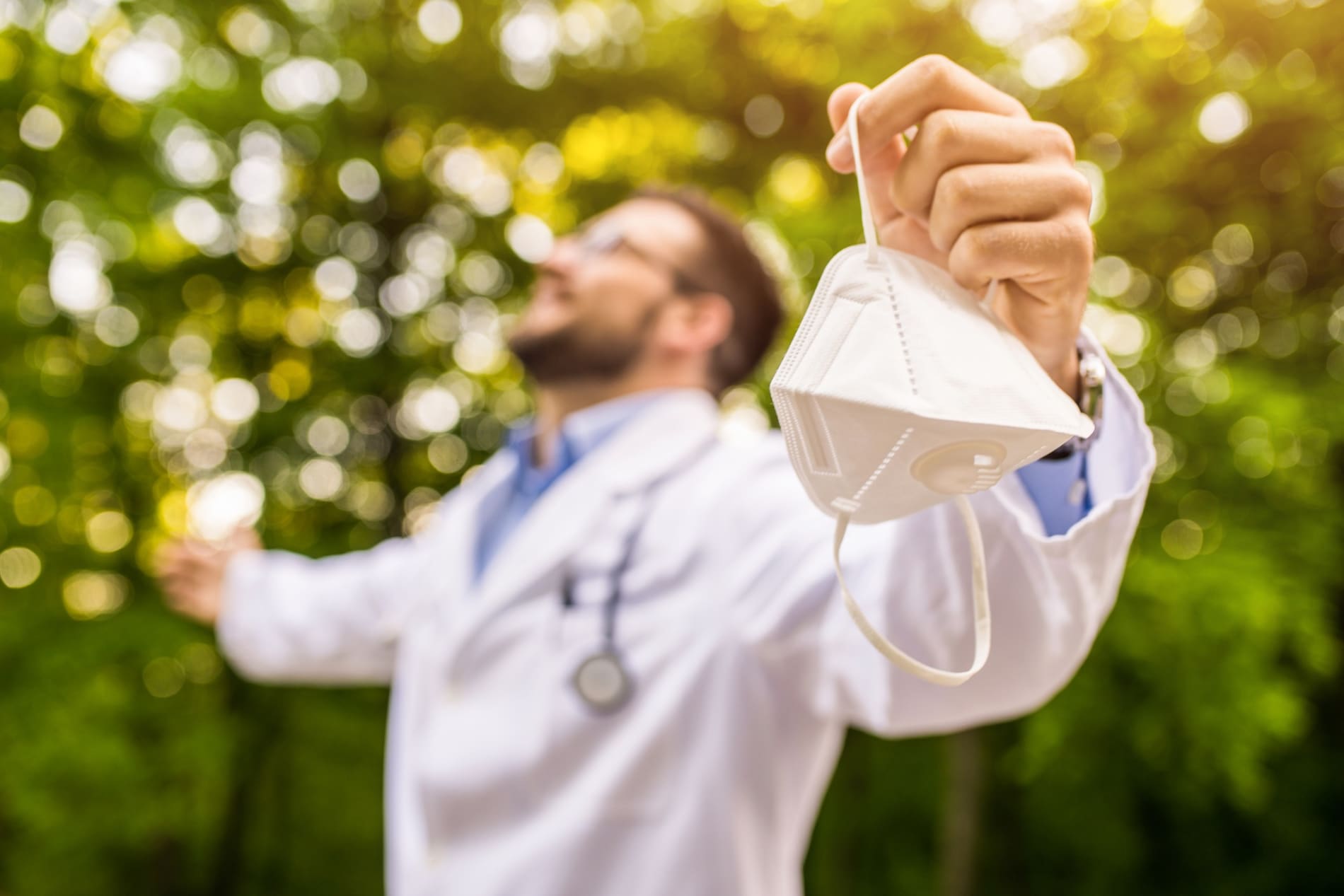 Happy doctor in an outdoor setting with his arms outstretched.