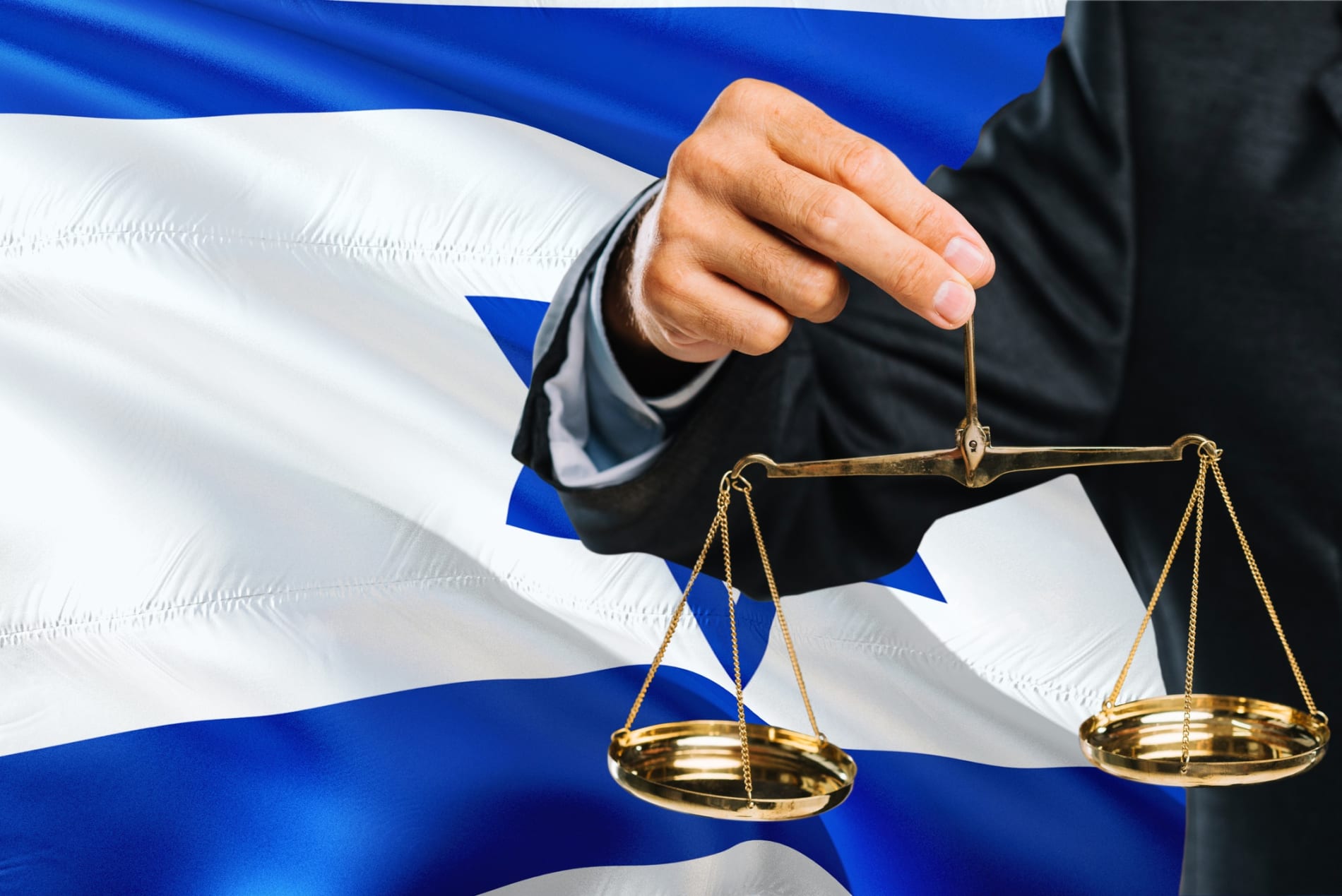 Man in a suit holds a scales of justice against a Israeli flag background.