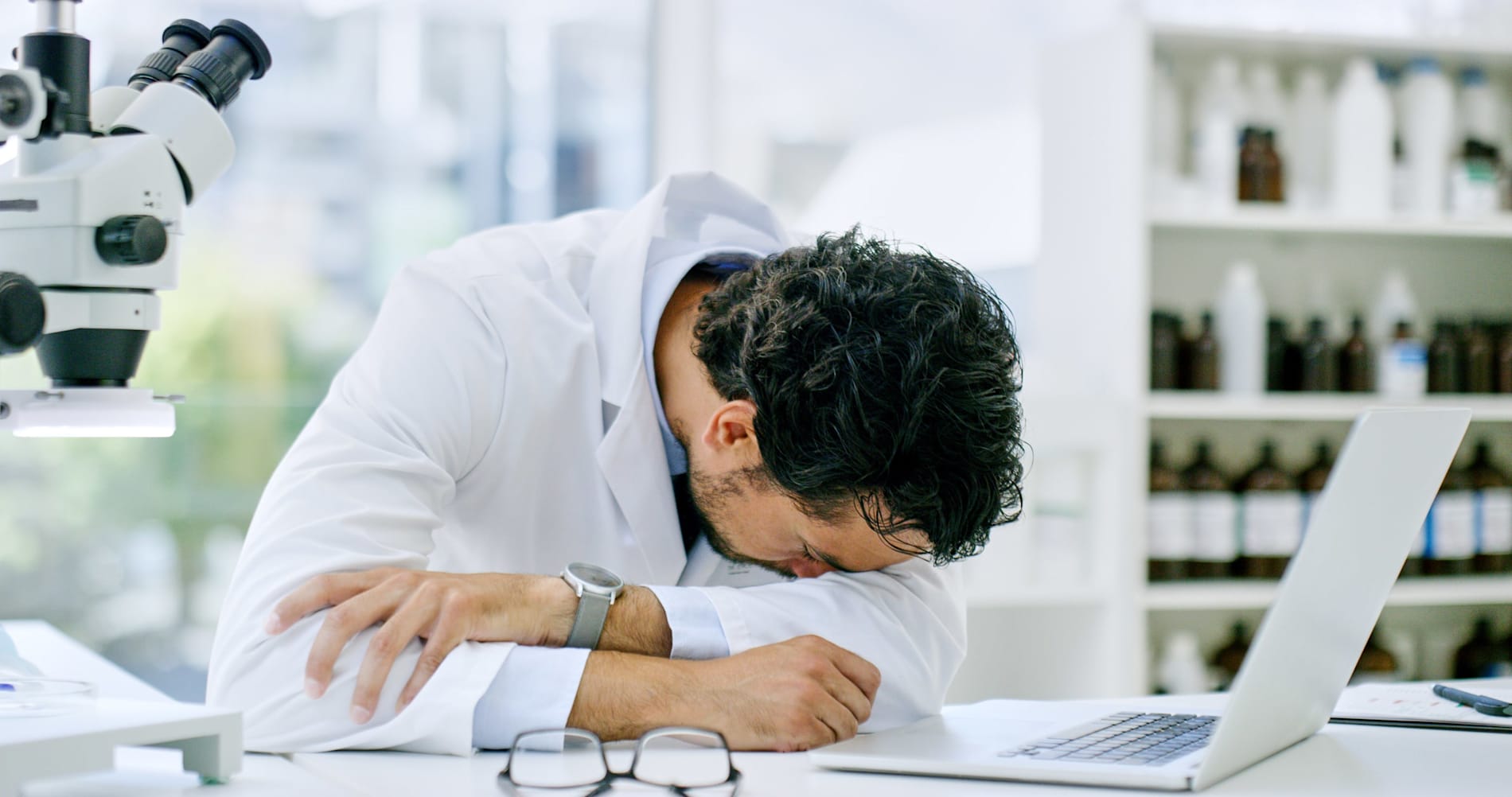 A young scientist lying with his head down on a table in a lab