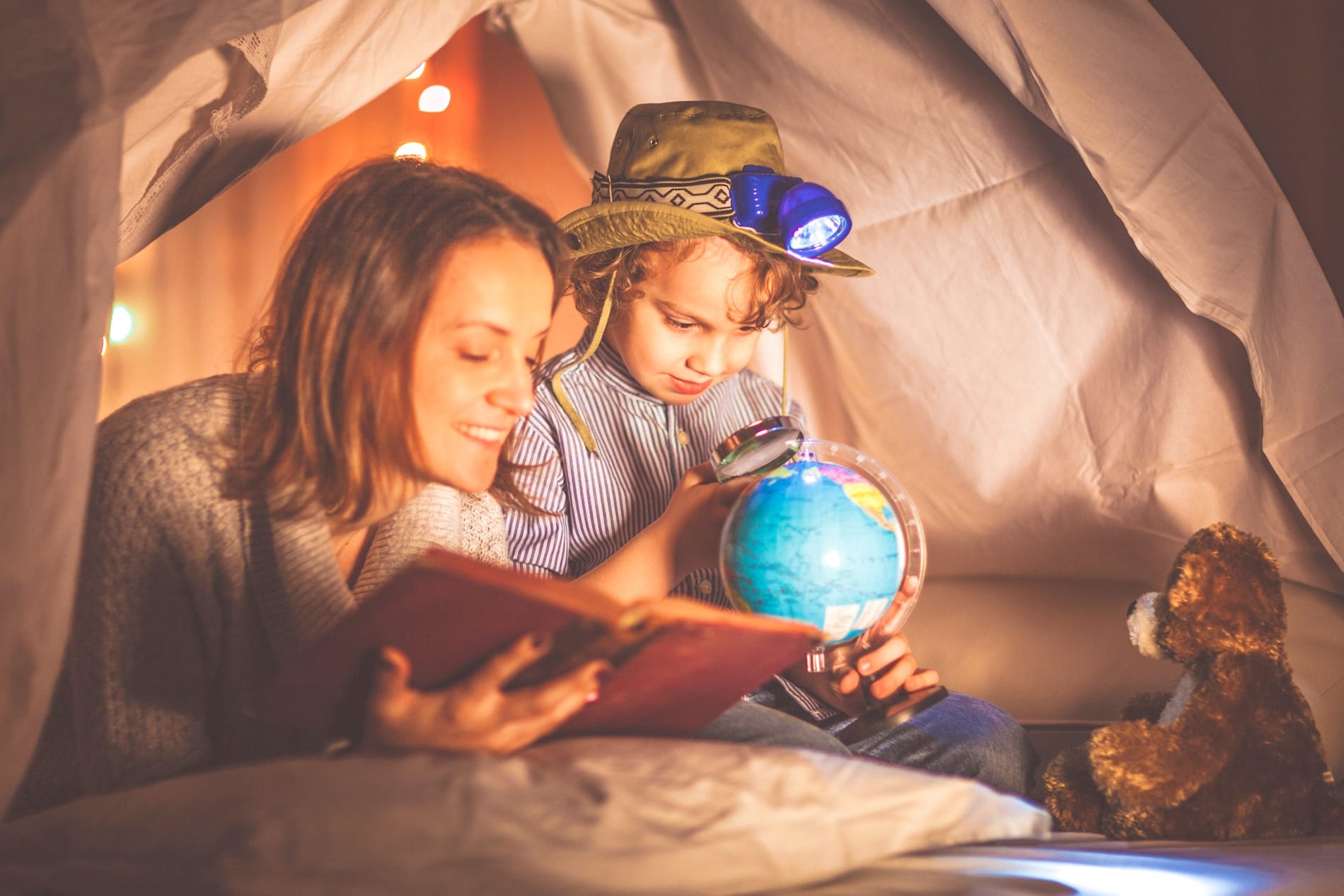 Mother reads a bedtime story to a child who is looking at a map of the world.