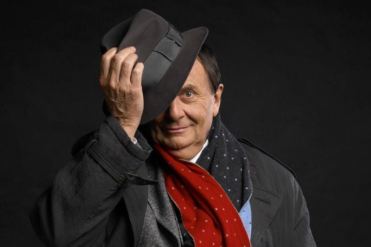 Barry Humphries tipping his hat towards the camera