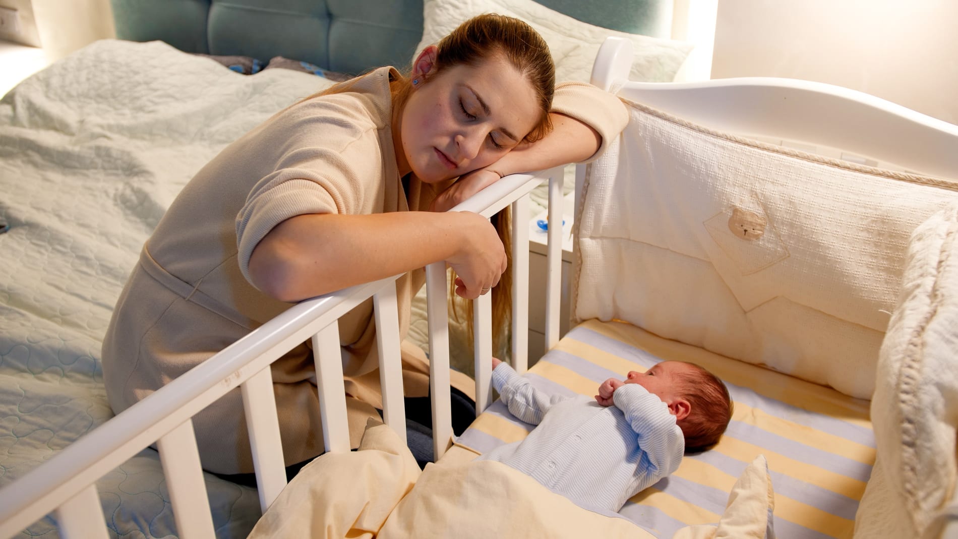 A mother asleep on the side of a cor while her baby sleeps