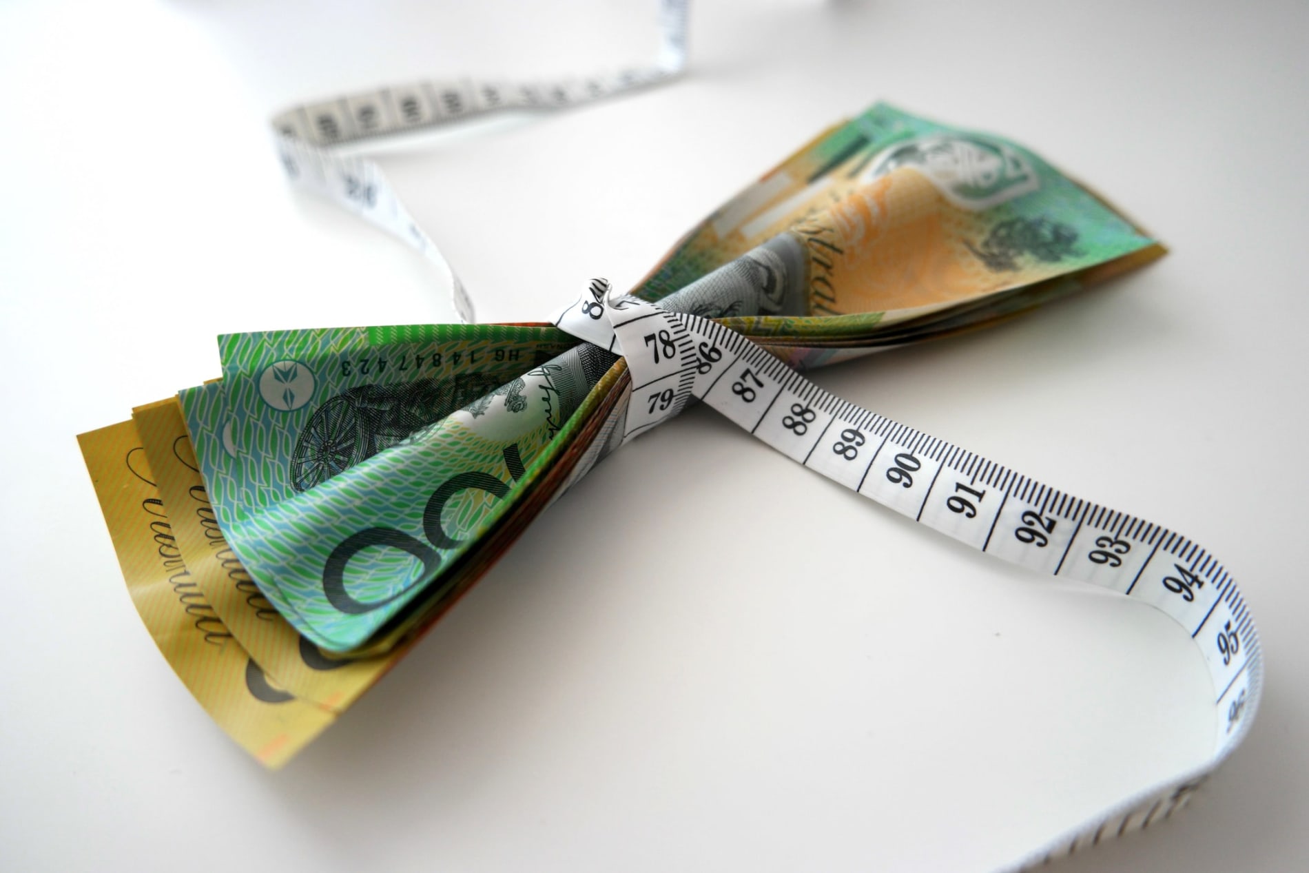 Australian banknotes squished tightly by tape measure